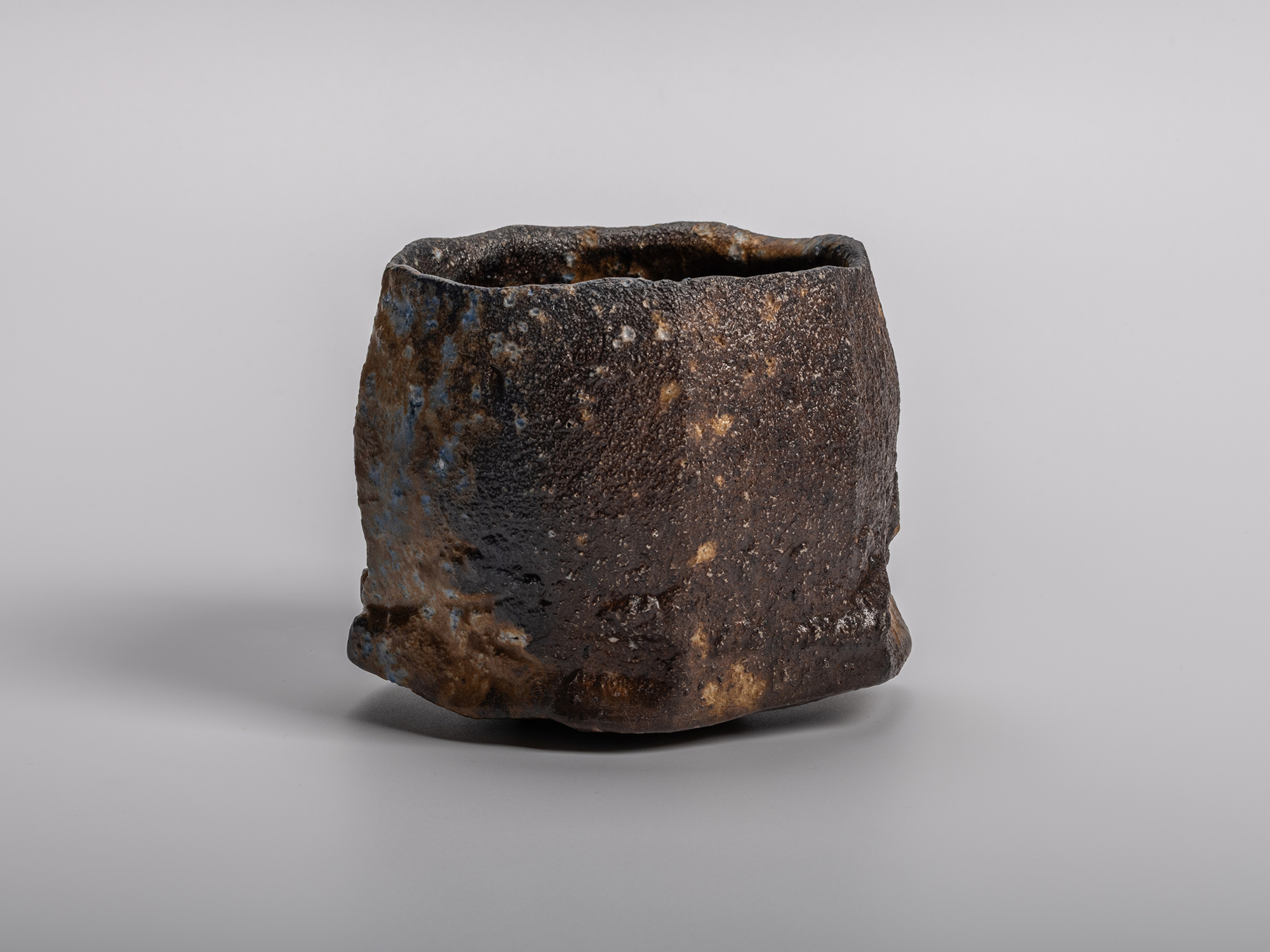 Profile view of a Black Tea Bowl by Ryuichi Kakurezaki. The stoneware features a rugged, asymmetrical...