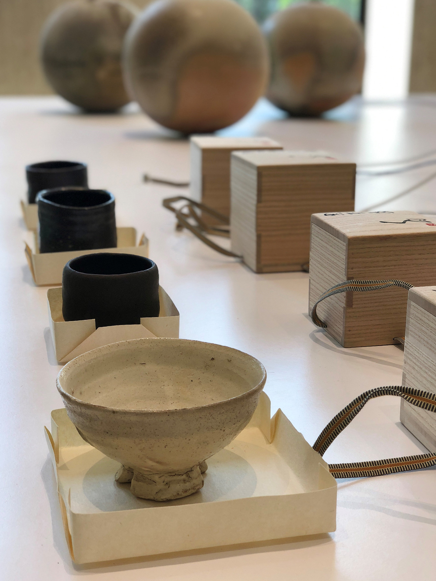 Tsujimura tea bowls and signed wooden boxes laid out for review, showcasing contemporary. Japanese...