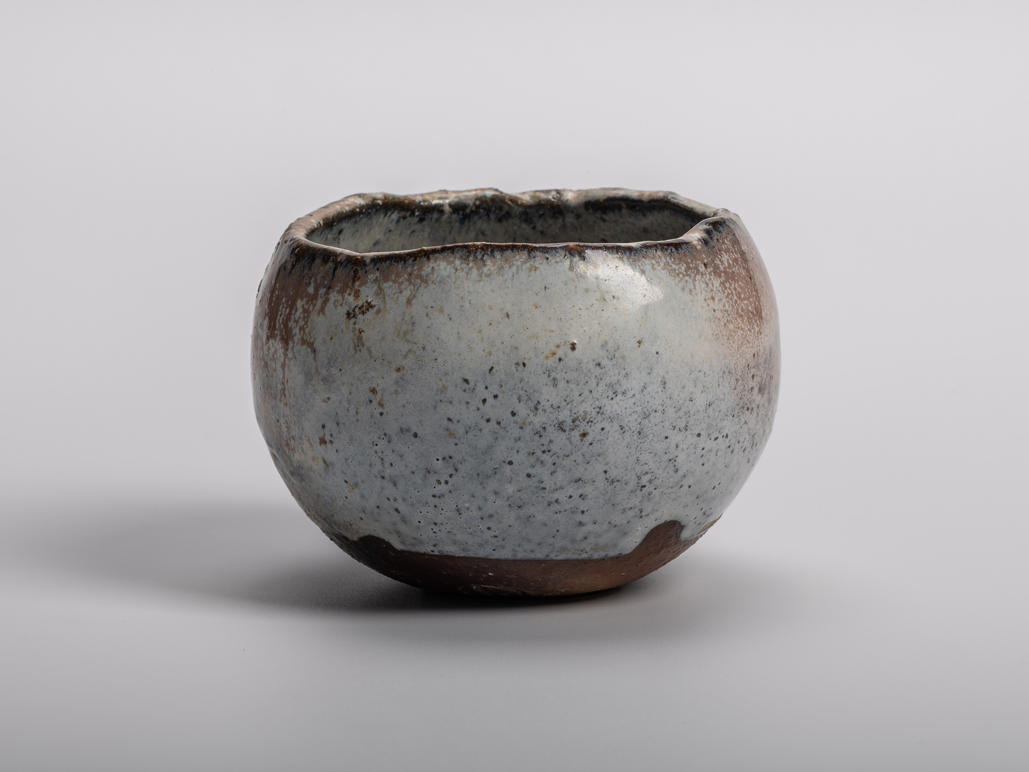 Masanao KANETA's Haikaburi Kurinuki Tea Bowl characterized by a rounded hand-carved form and mottled...