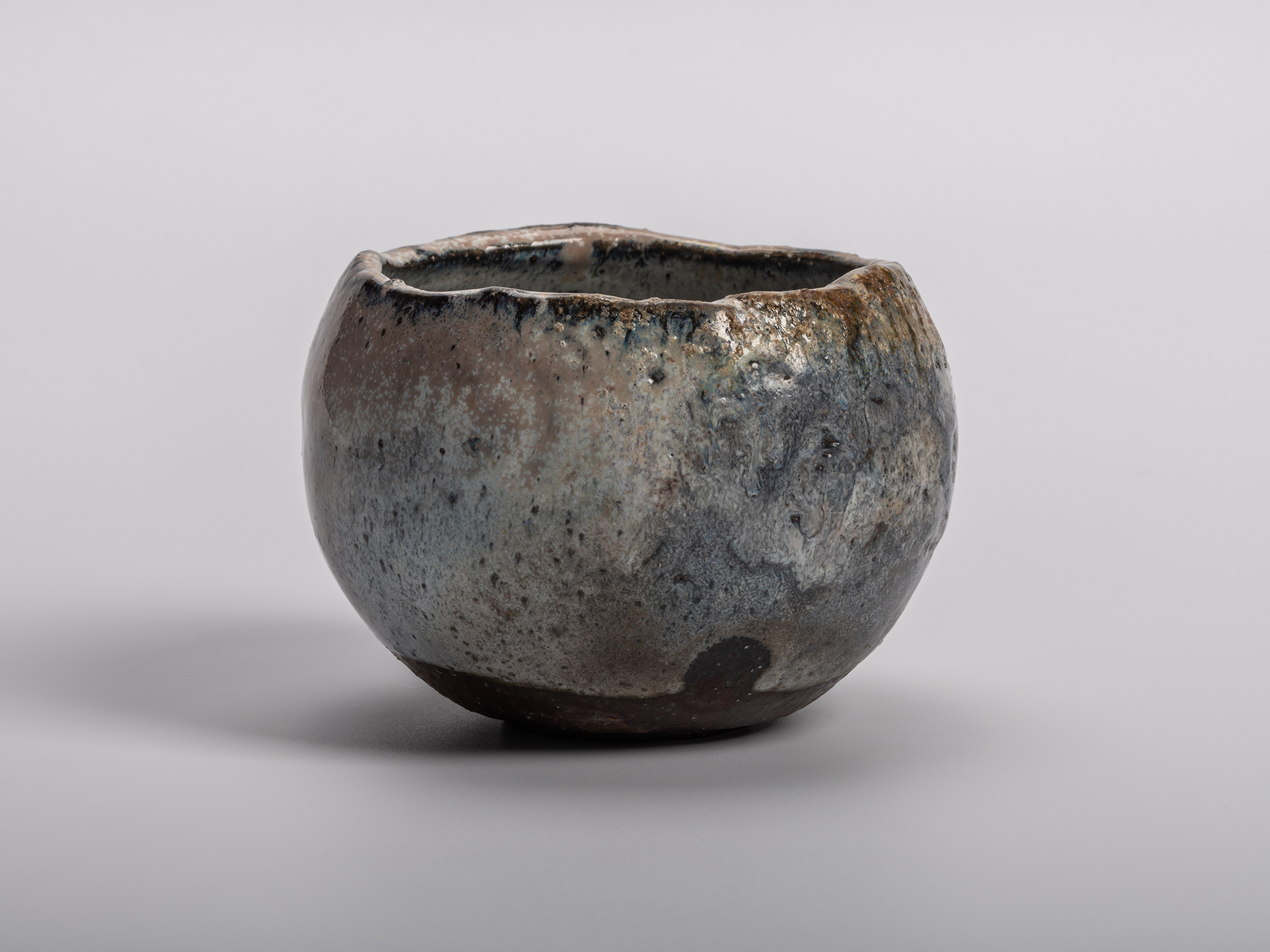 Masanao KANETA's Haikaburi Kurinuki Tea Bowl characterized by a rounded hand-carved form and mottled...