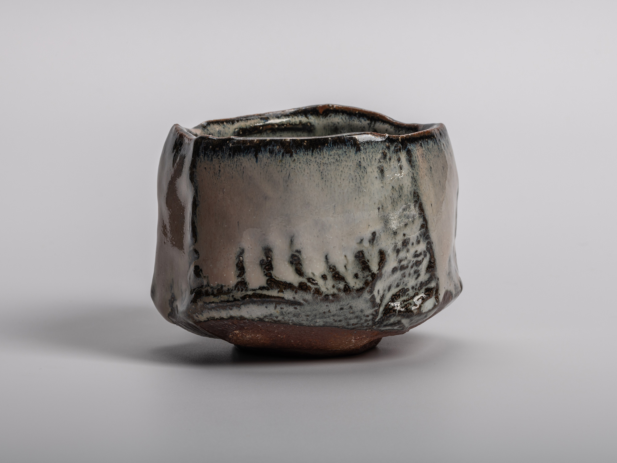 Masanao Kaneta’s Haikaburi Kurinuki tea bowl with hand-carved faceted form, flowing ash-fired glaze...
