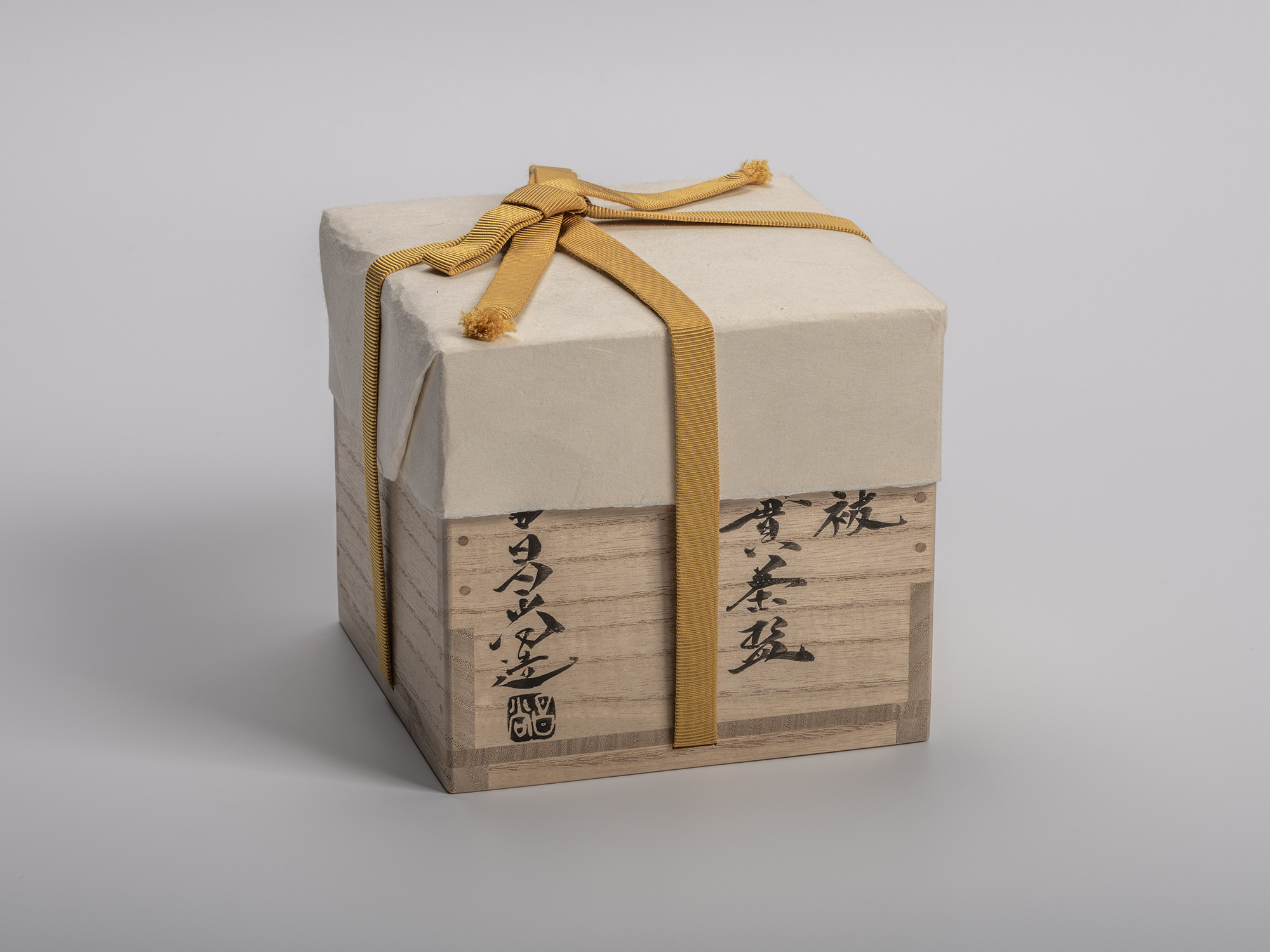 Wooden box for Masanao Kaneta’s Haikaburi Kurinuki tea bowl, shown with mustard yellow cord and...