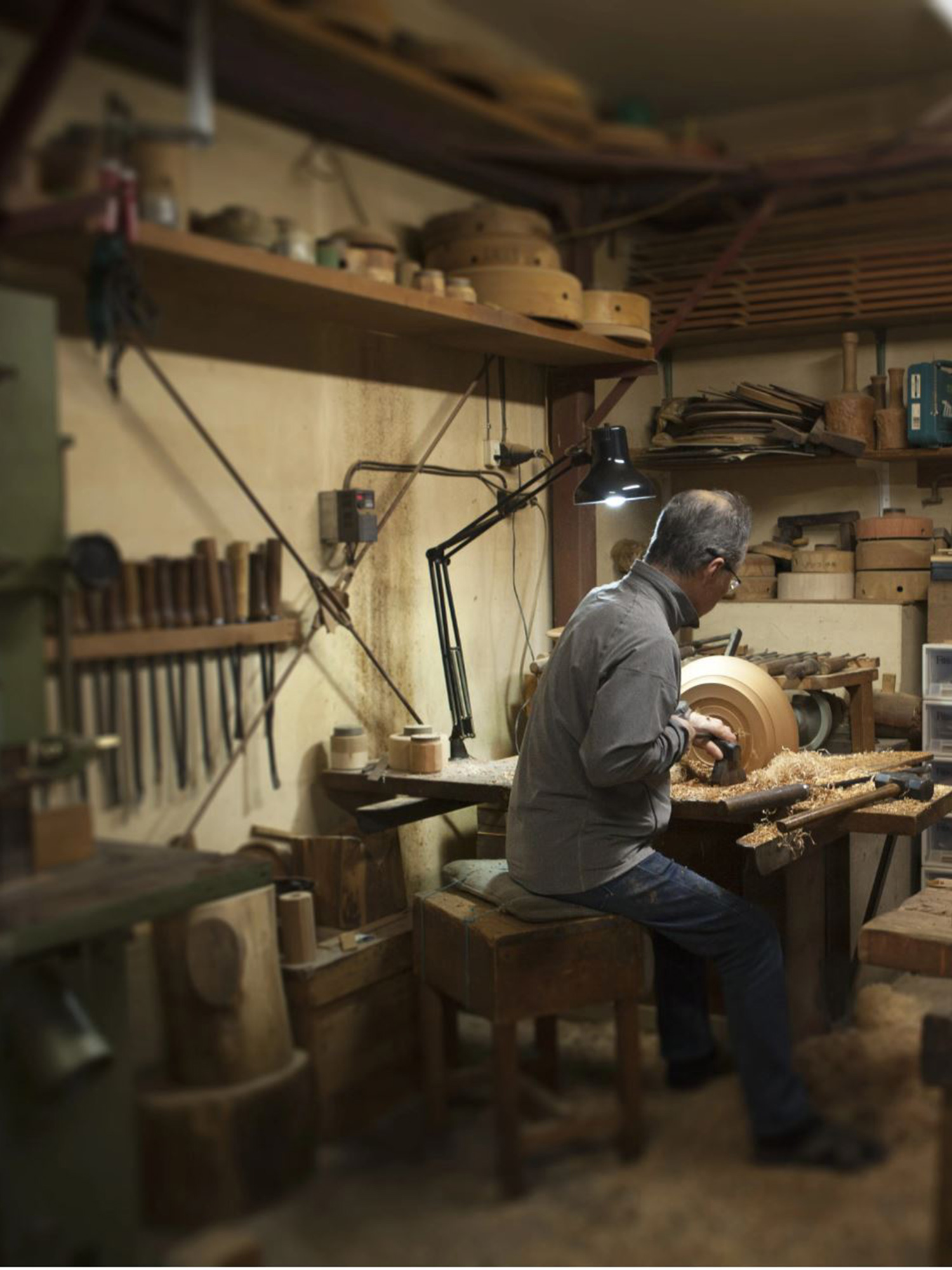 Jihei Murase in a traditional studio with tools along the wall. Artists is actively shaping an...