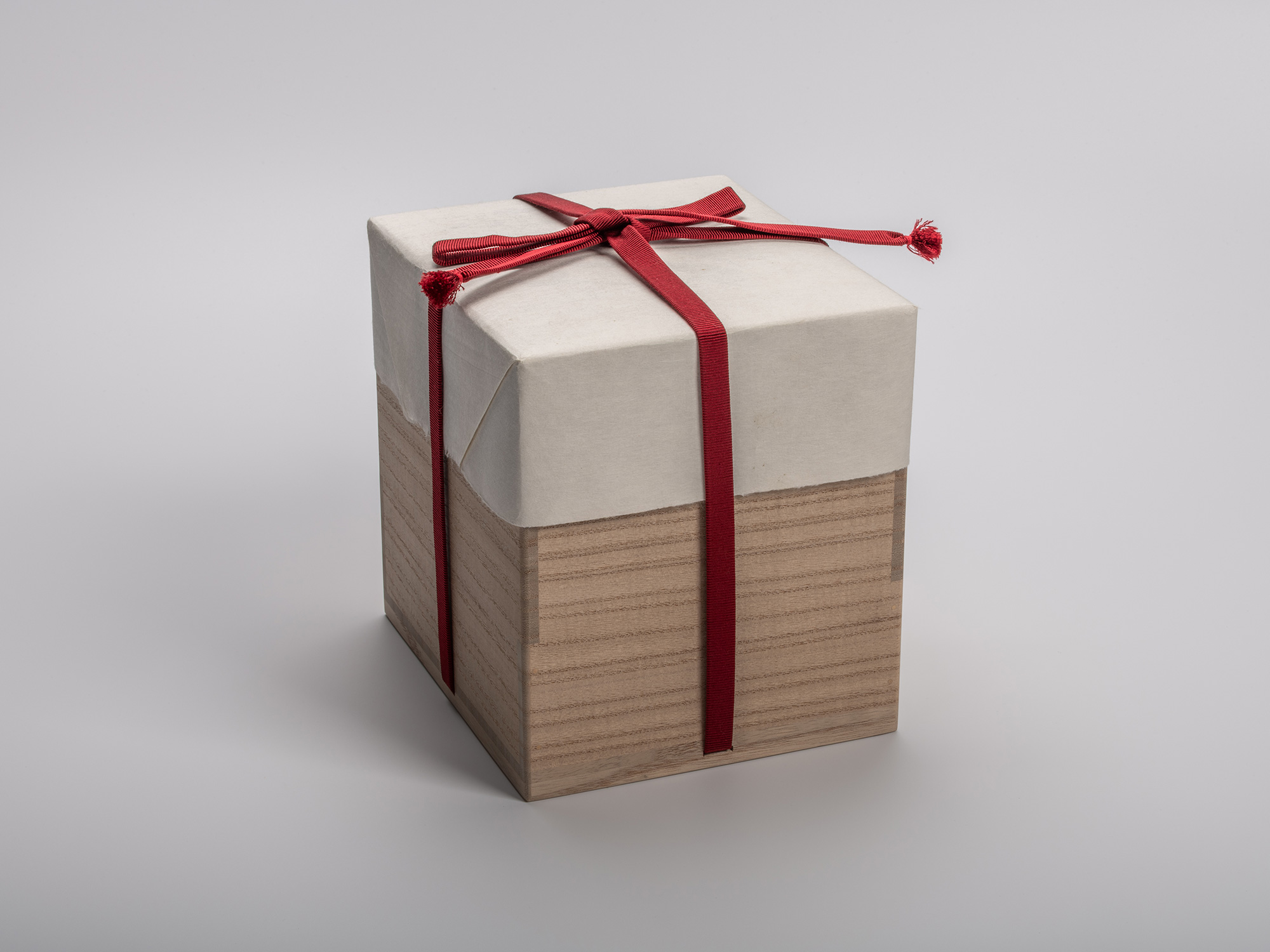 Square wooden tomobako (artist-signed storage box). The box is half-wrapped in natural paper and...