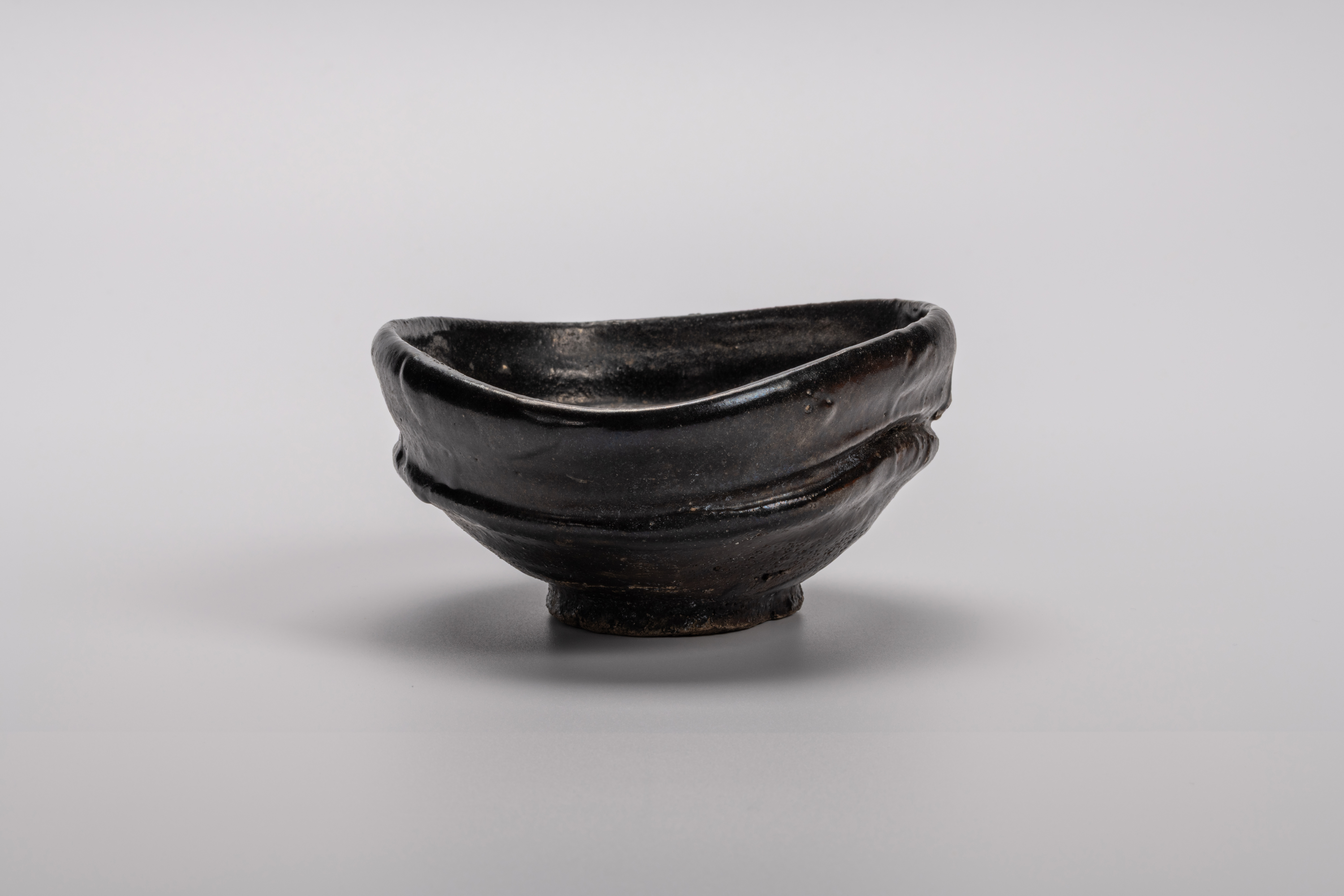 Oribe Kuro Chawan by Shiro Tsujimura, a hand-formed black tea bowl with oval contours and a rich,...