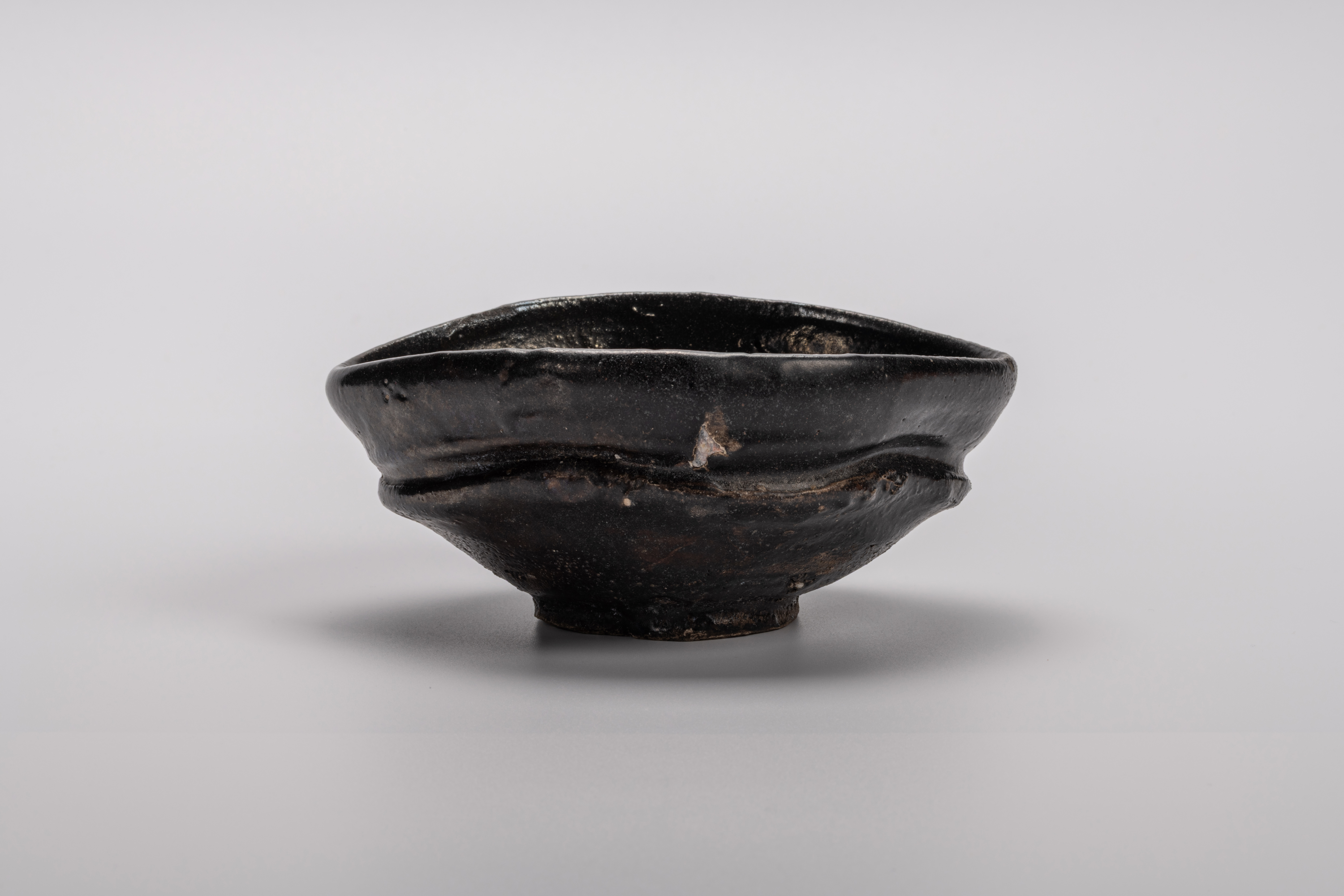 Oribe Kuro Chawan by Shiro Tsujimura, a hand-formed black tea bowl with oval contours and a rich,...