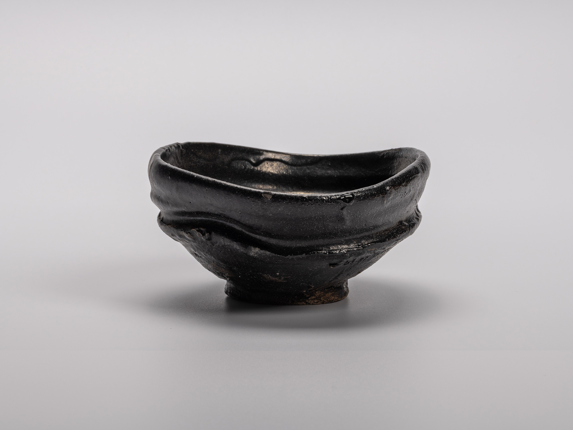 Oribe Kuro Chawan by Shiro Tsujimura, a hand-formed black tea bowl with oval contours and a rich,...