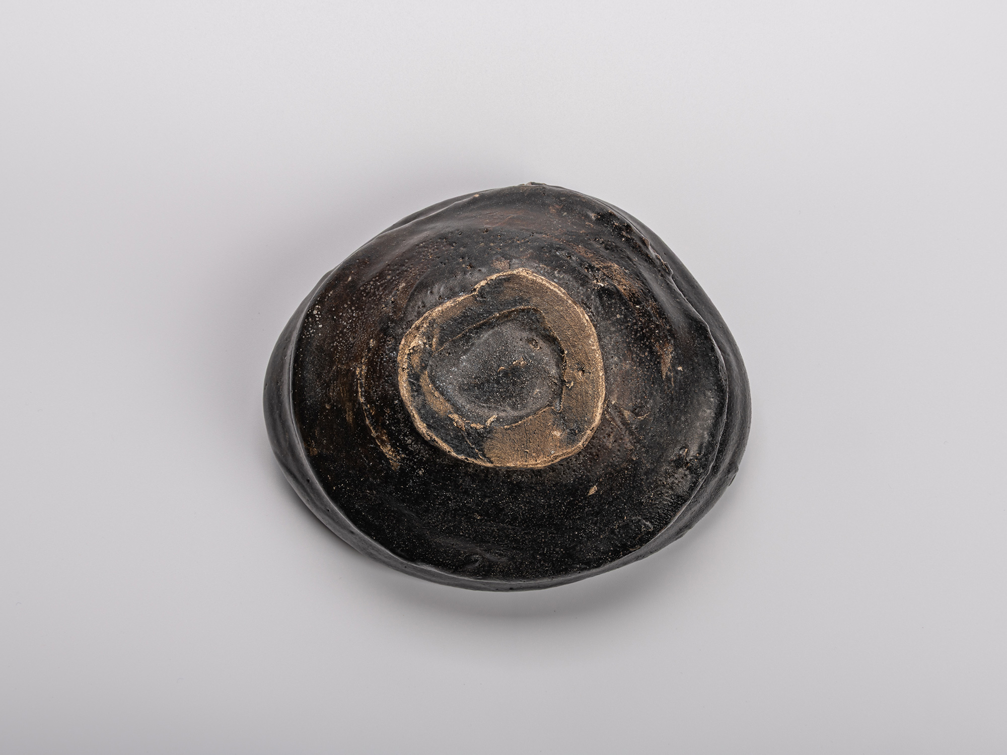 Foot (kōdai) of Shiro Tsujimura’s Oribe Kuro Chawan, showing the unglazed circular base surrounded...