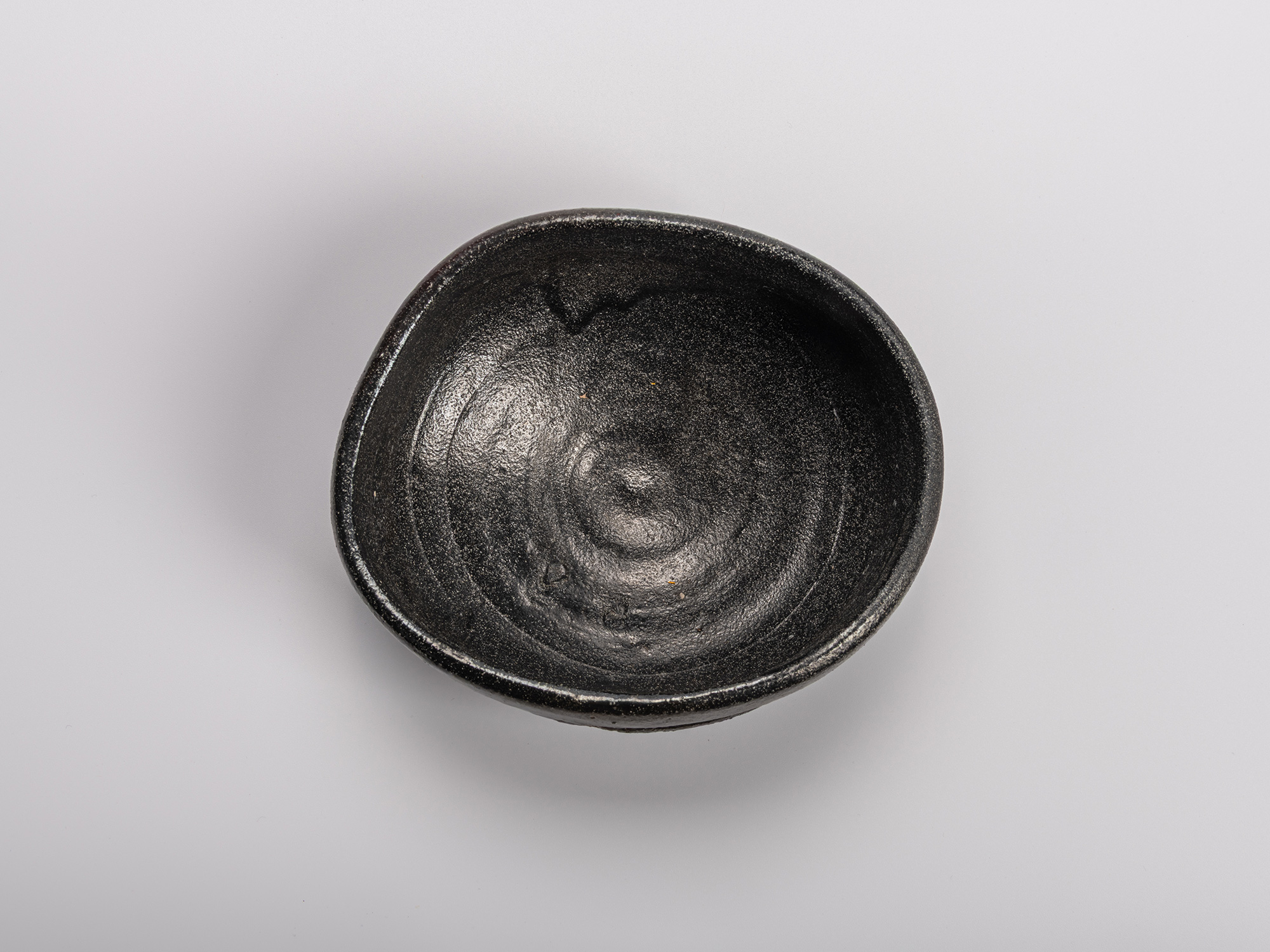 Interior (mikomi) of Shiro Tsujimura’s Oribe Kuro Chawan, showing the textured black glaze and...