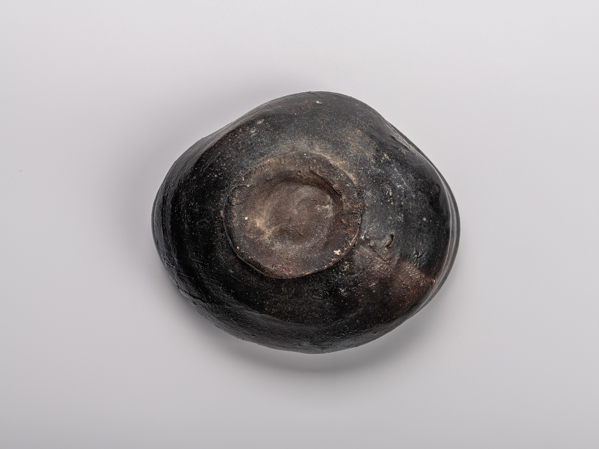 Foot (kōdai) of Shiro Tsujimura’s Oribe Kuro Chawan, showing the unglazed central base surrounded...