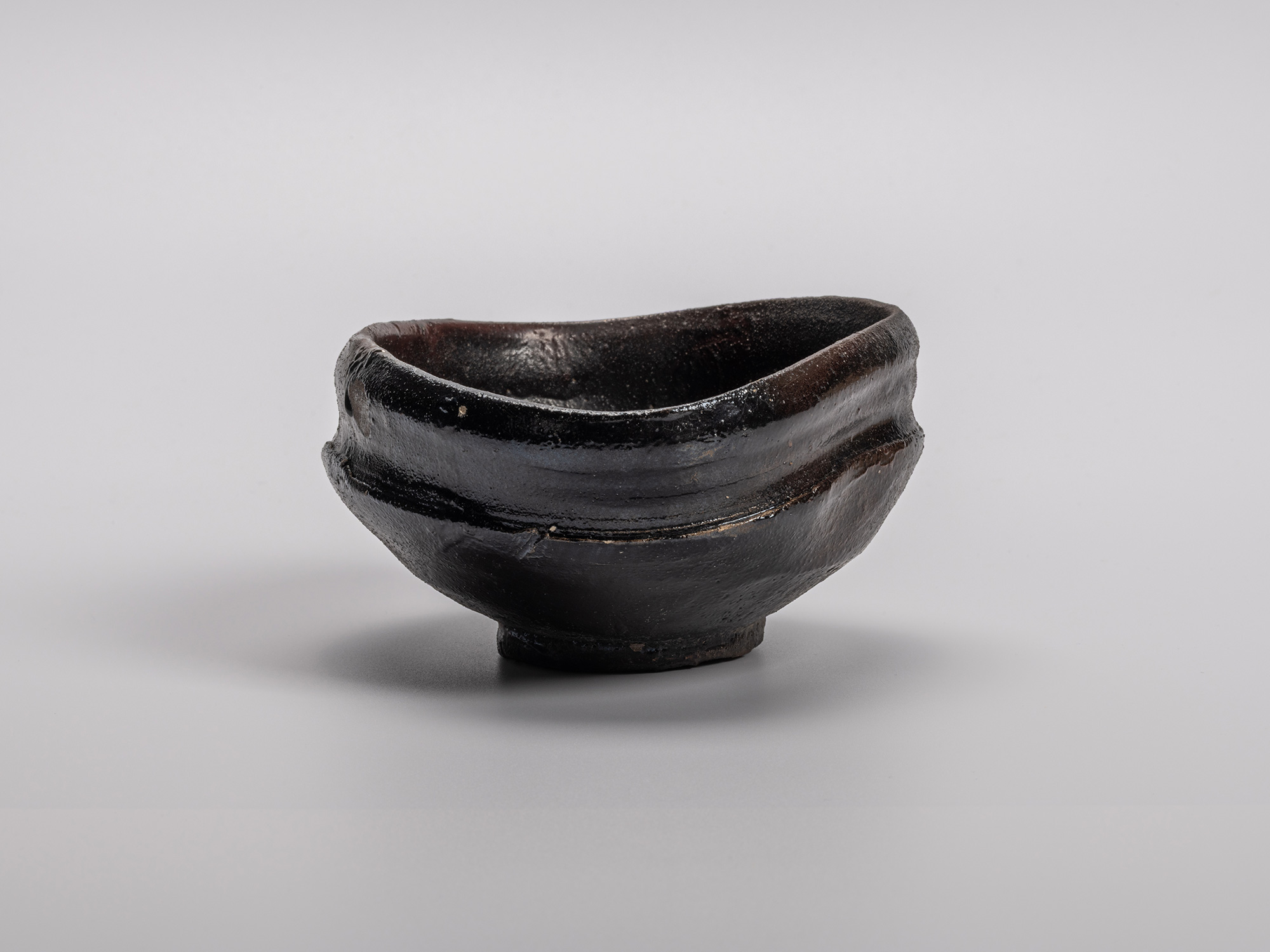 Oribe Kuro Chawan by Shiro Tsujimura, a hand-shaped black tea bowl featuring subtle distortions,...
