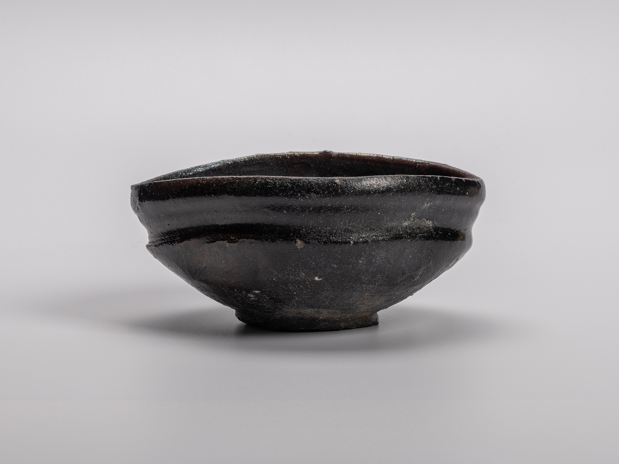 Oribe Kuro Chawan by Shiro Tsujimura, a hand-shaped black tea bowl featuring subtle distortions,...