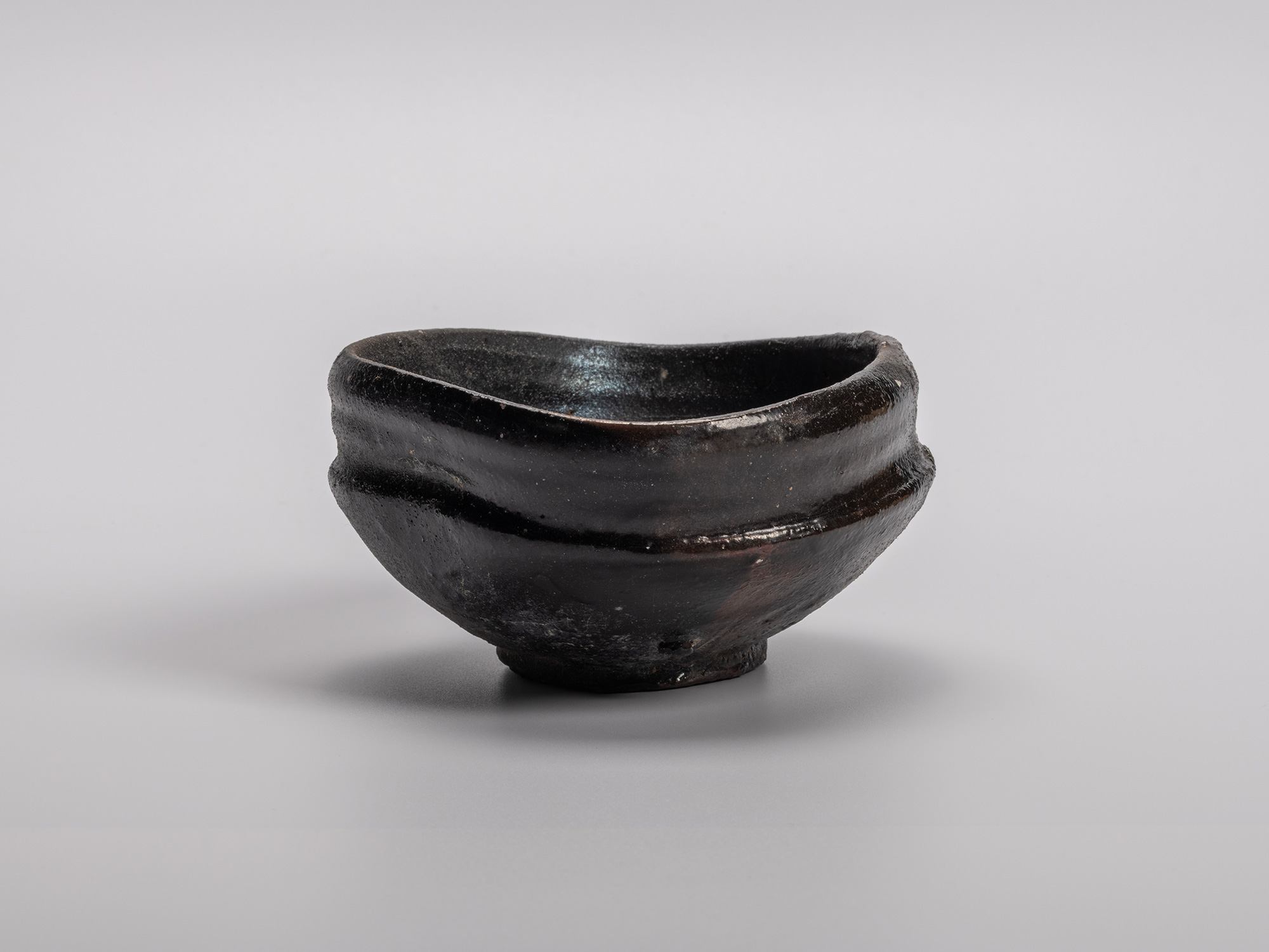 Oribe Kuro Chawan by Shiro Tsujimura, a hand-shaped black tea bowl featuring subtle distortions,...