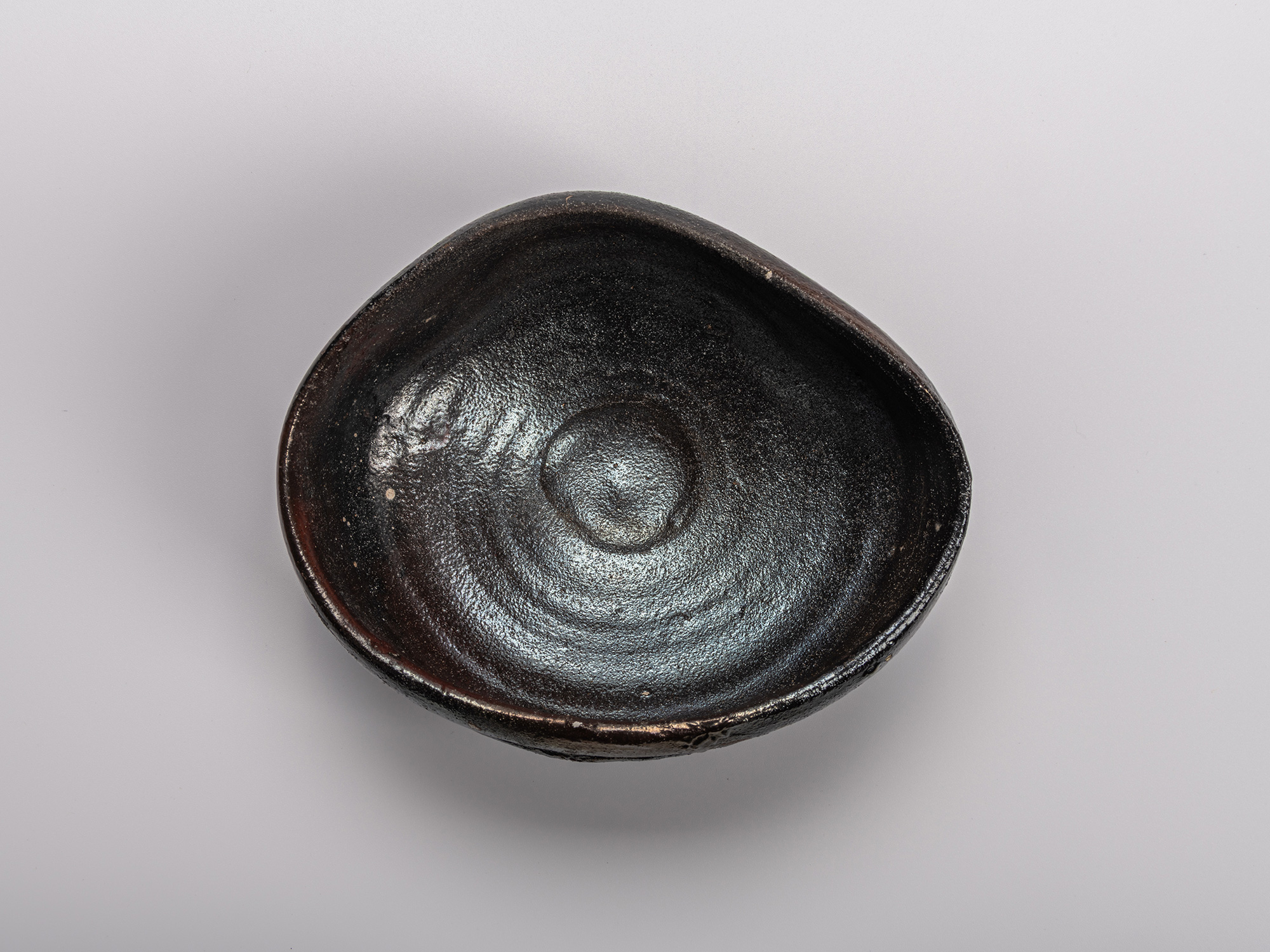 Interior (mikomi) of Shiro Tsujimura’s Oribe Kuro Chawan, showing the hand-formed black glaze surface...