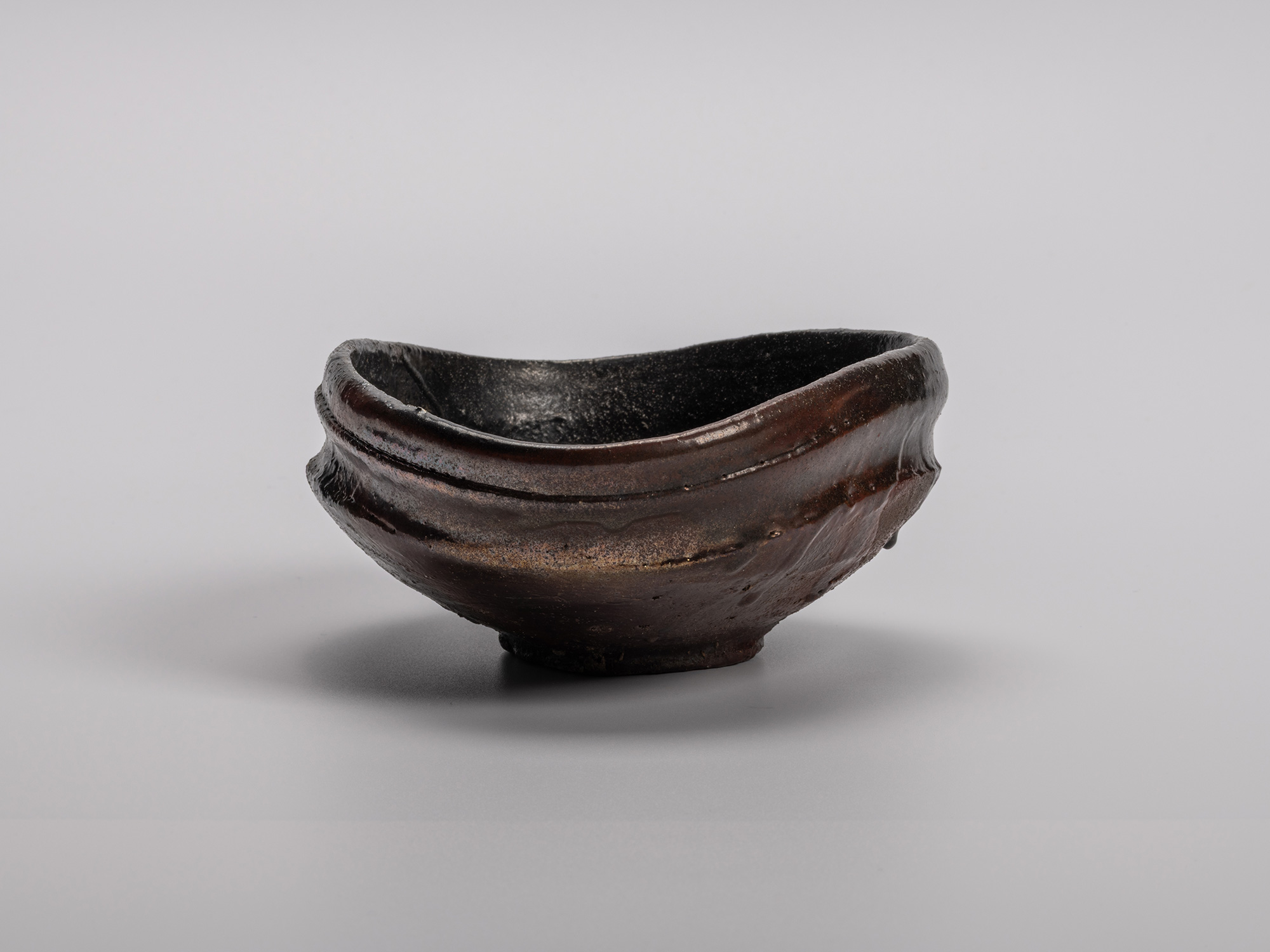Oribe Kuro Chawan by Shiro Tsujimura, a hand-formed black tea bowl with a soft oval profile, raised...