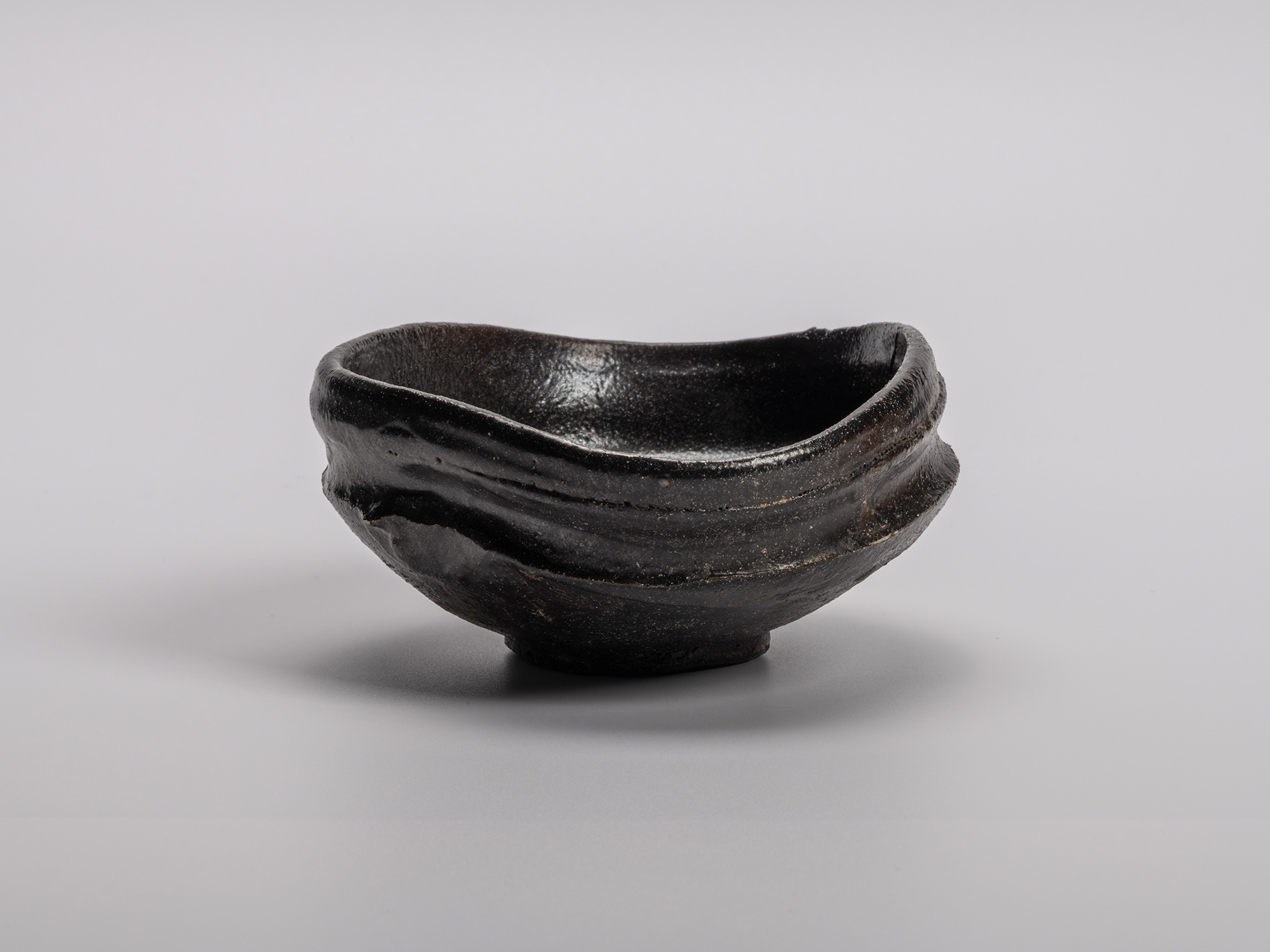 Oribe Kuro Chawan by Shiro Tsujimura, a hand-formed black tea bowl with a soft oval profile, raised...
