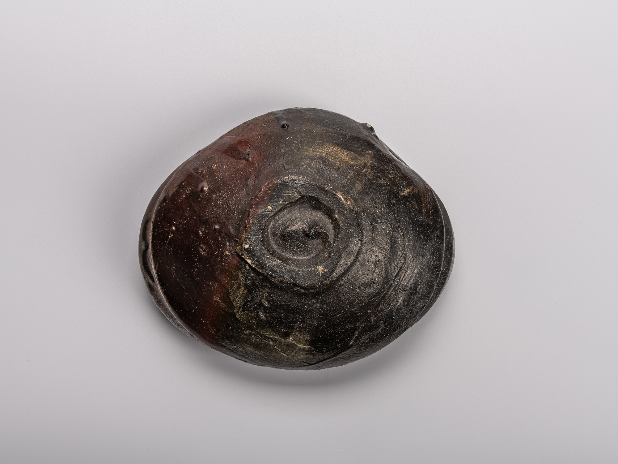 Foot (kōdai) of Shiro Tsujimura’s Oribe Kuro Chawan, showing the unglazed spiral base with textured...