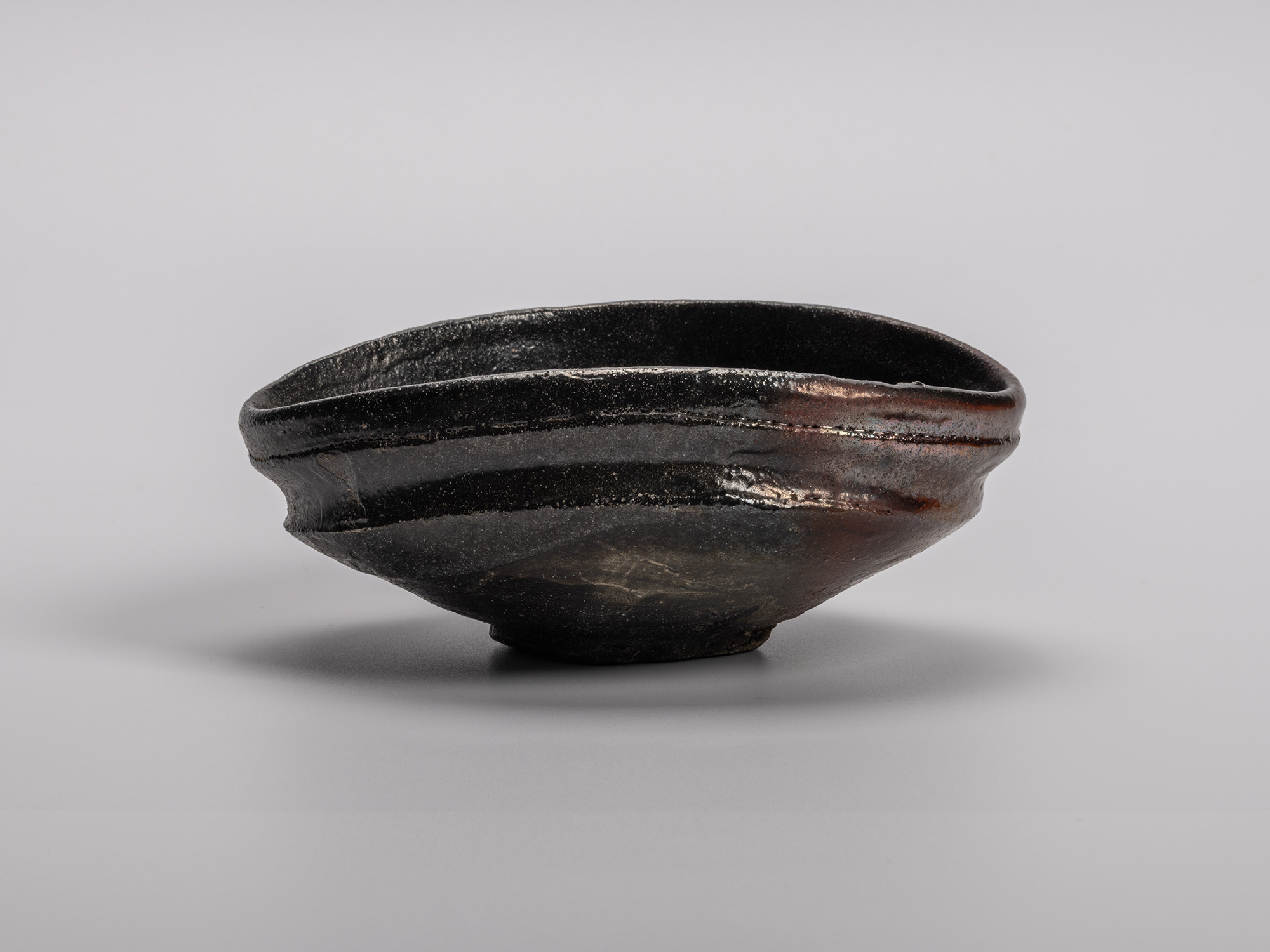 Oribe Kuro Chawan by Shiro Tsujimura, a hand-formed black tea bowl with a soft oval profile, raised...