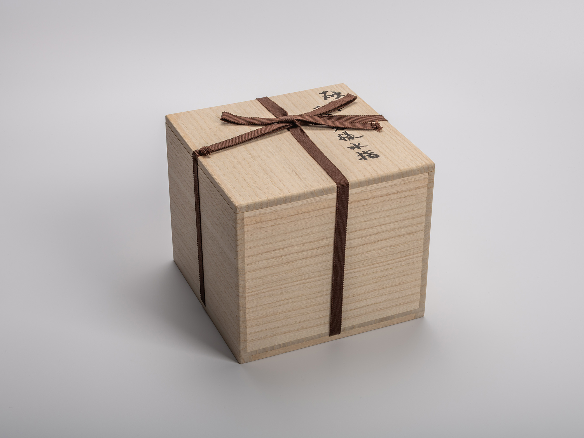 Wooden storage box for Uozumi Iraku III’s Sahari Water Jug, tied with a brown ribbon and marked...