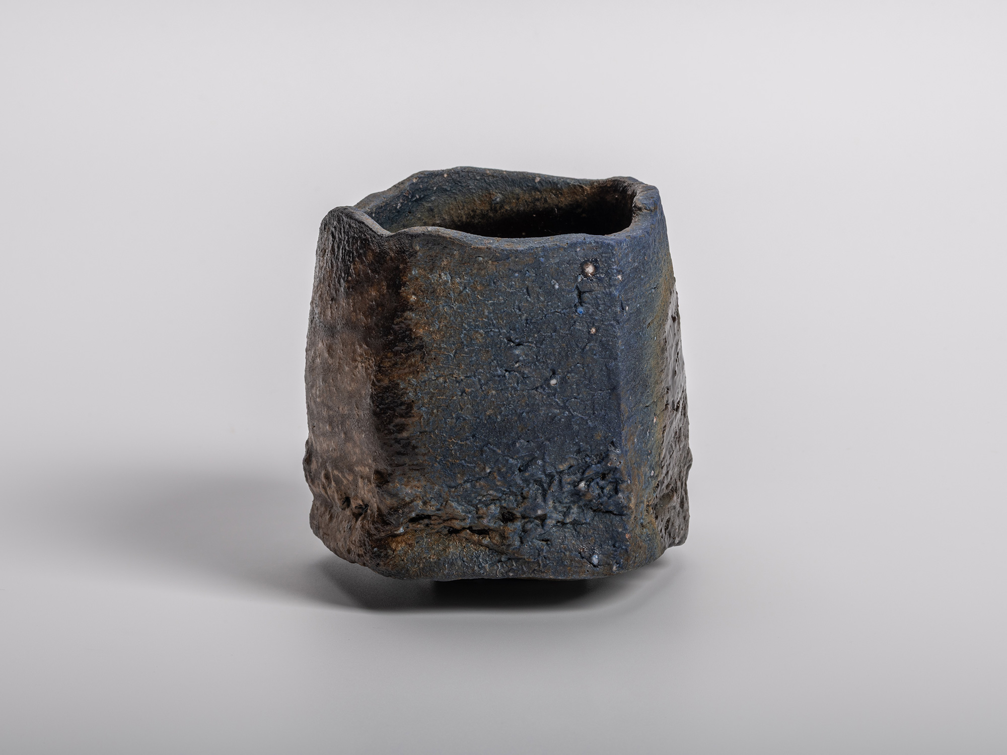 Kakurezaki Ryuichi tea bowl Una Mistura showing its sculptural square form with textured blue-to-earth-toned...