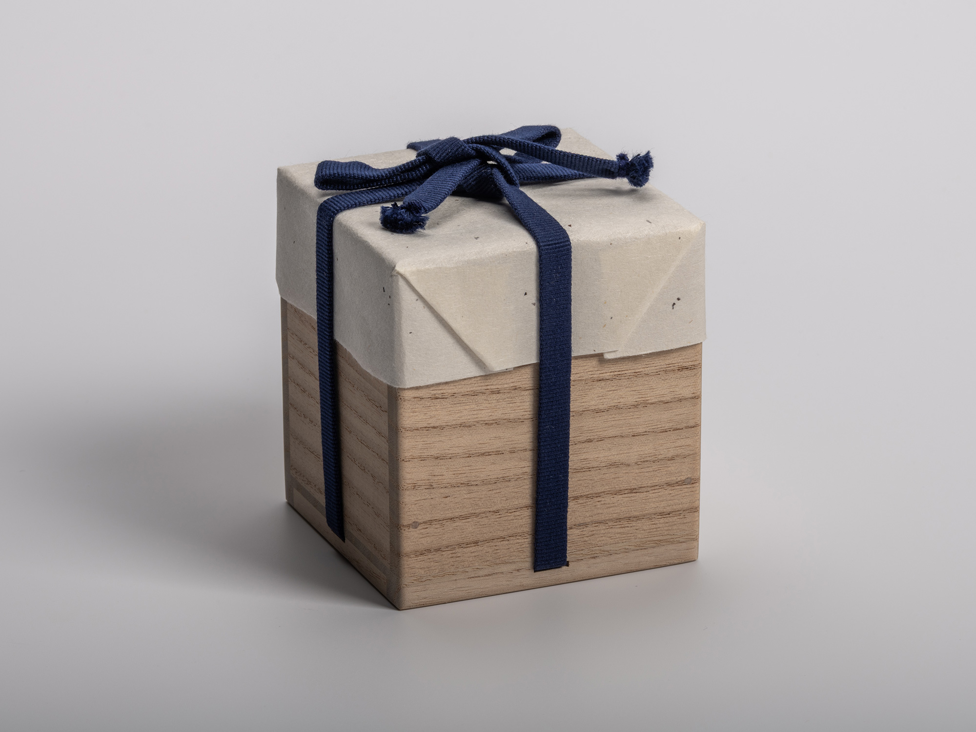 Square wooden tomobako (artist-signed storage box) by ceramic artist, shown with its navy-blue...
