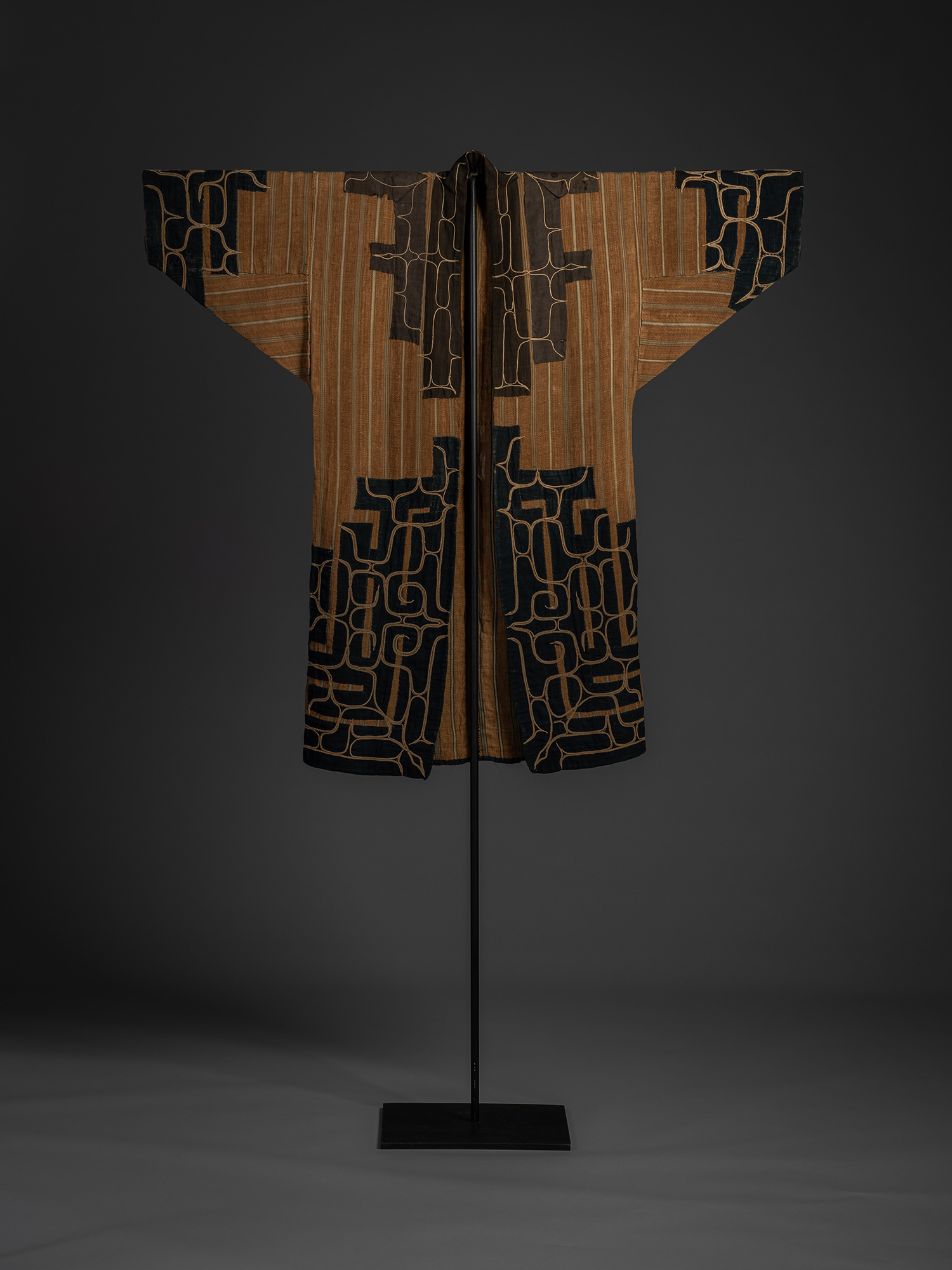 Mid-19th-century Ainu attush robe made of woven elm bark fiber, displayed frontally on a stand,...