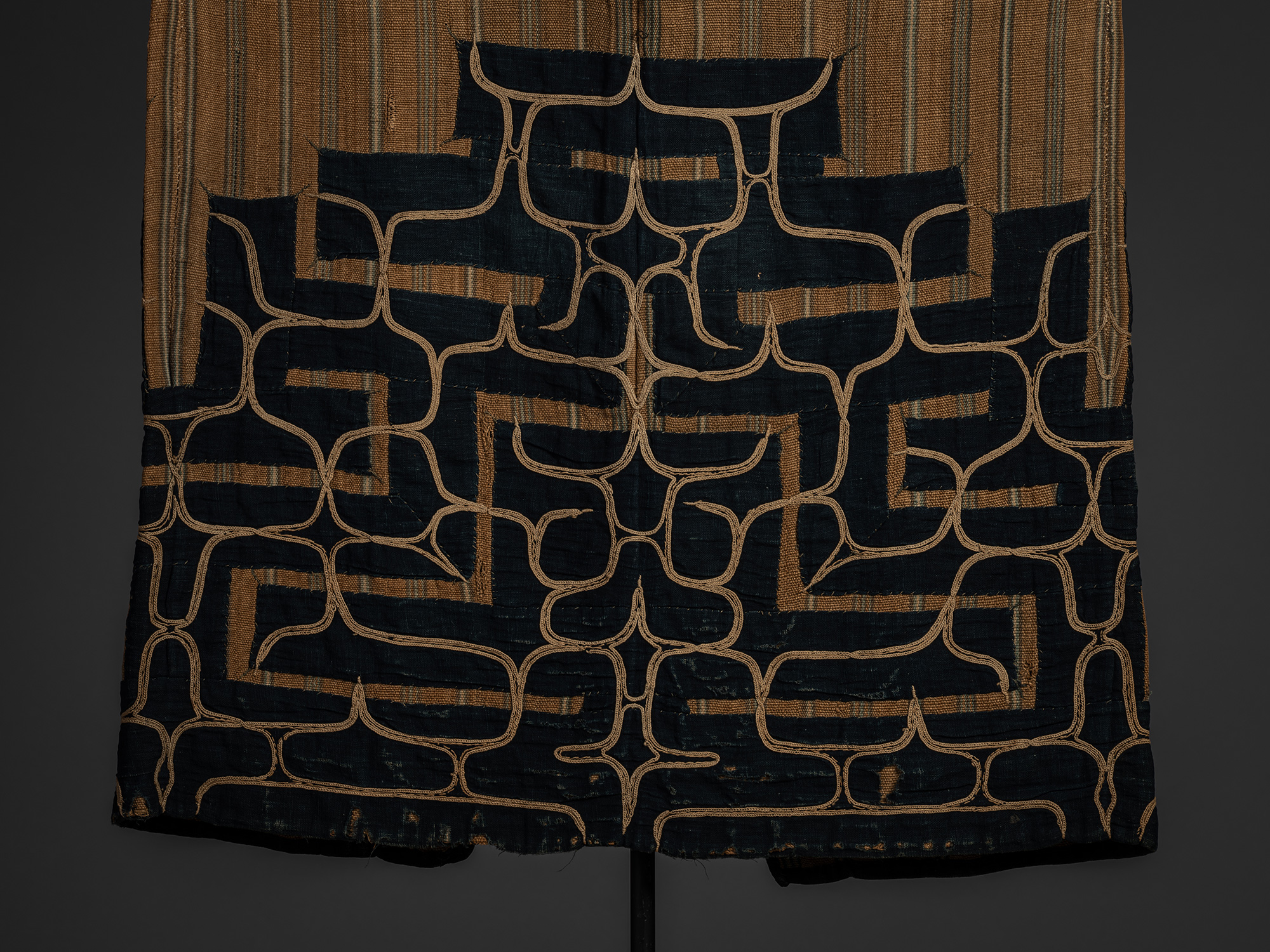 Detail of bottom back of a mid-19th-century Ainu attush robe, showing indigo-dyed cotton appliqué...