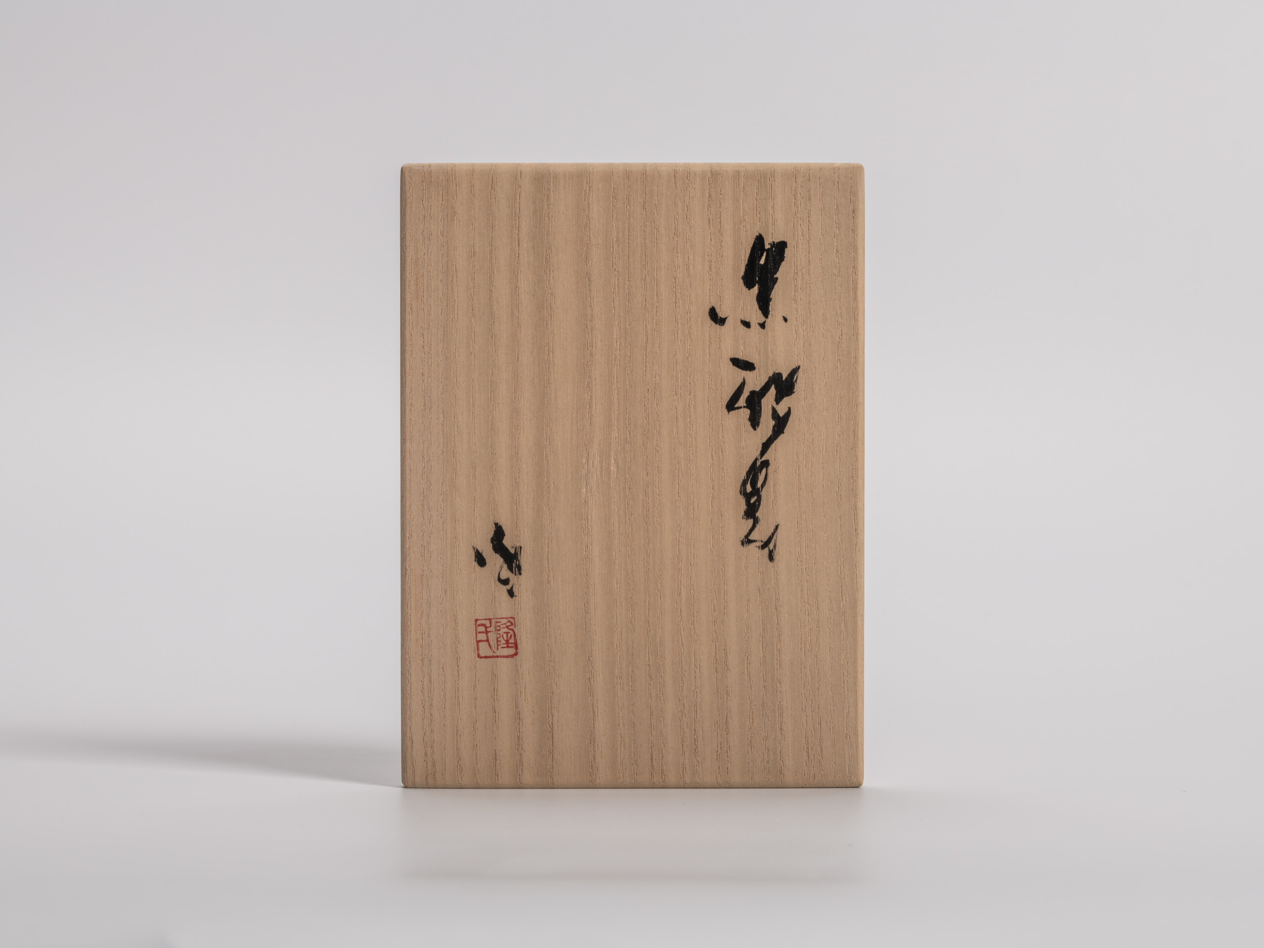 Wooden presentation box lid for a tokkuri by Ryuichi Kakurezaki, shown frontally. The pale kiri...