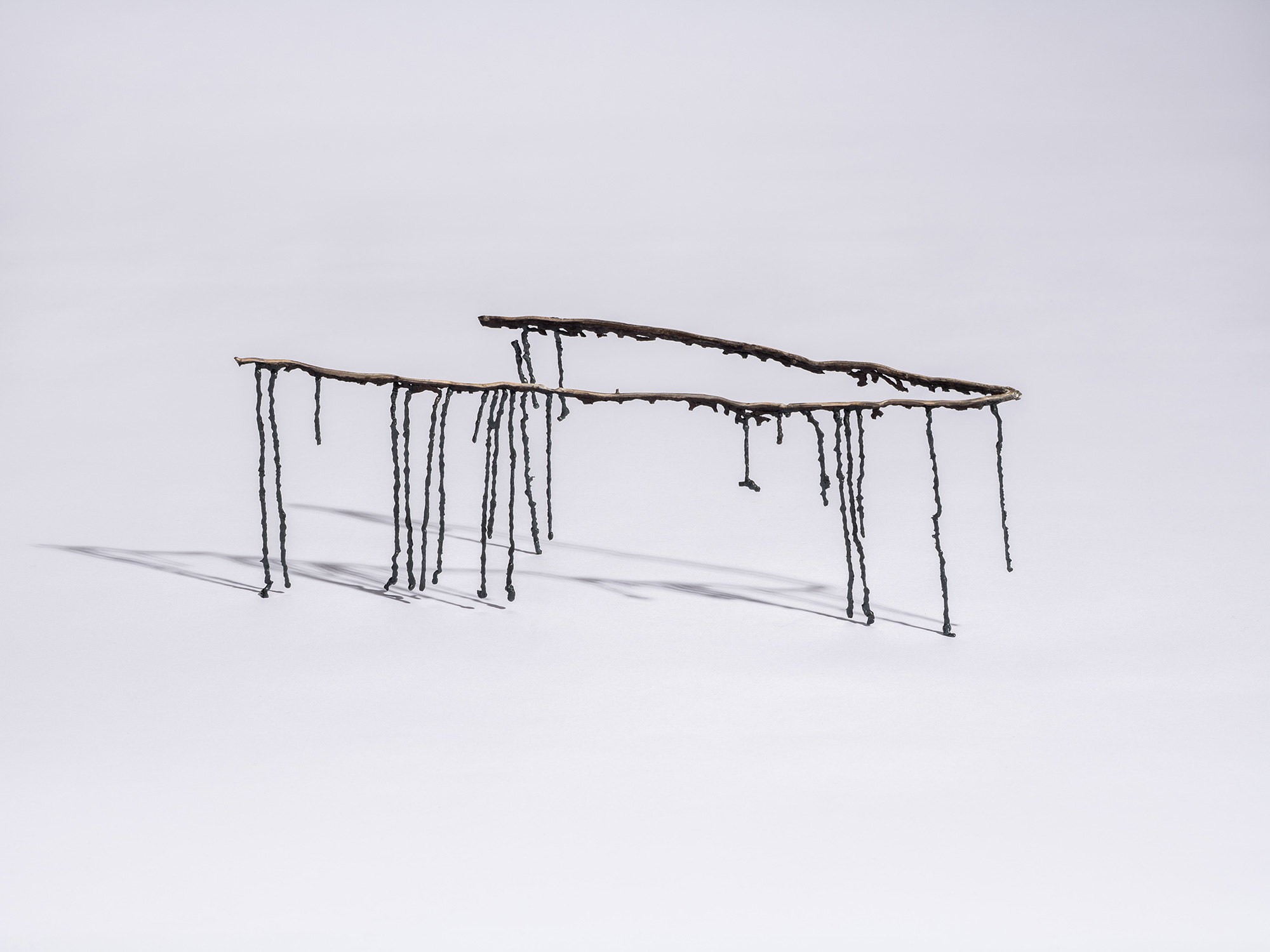 Iron sculpture Étranger by Aki Rusu, featuring two slender, irregular iron beams suspended on elongated,...