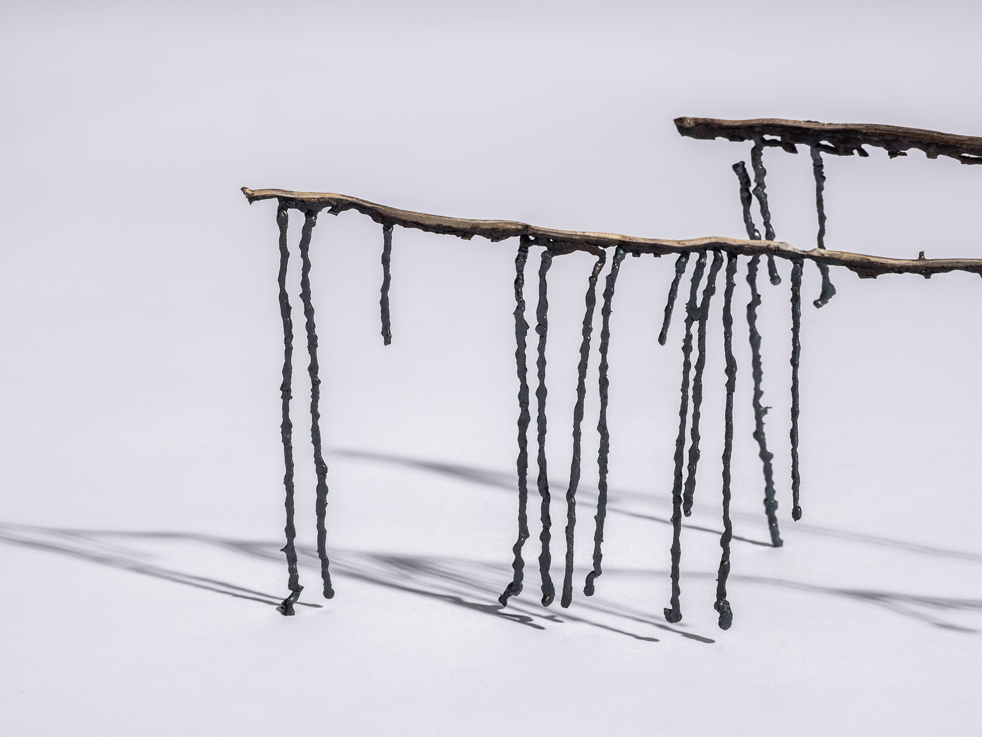 Detail showing of iron sculpture Étranger by Aki Rusu, showcasing delicate iron beams suspended...