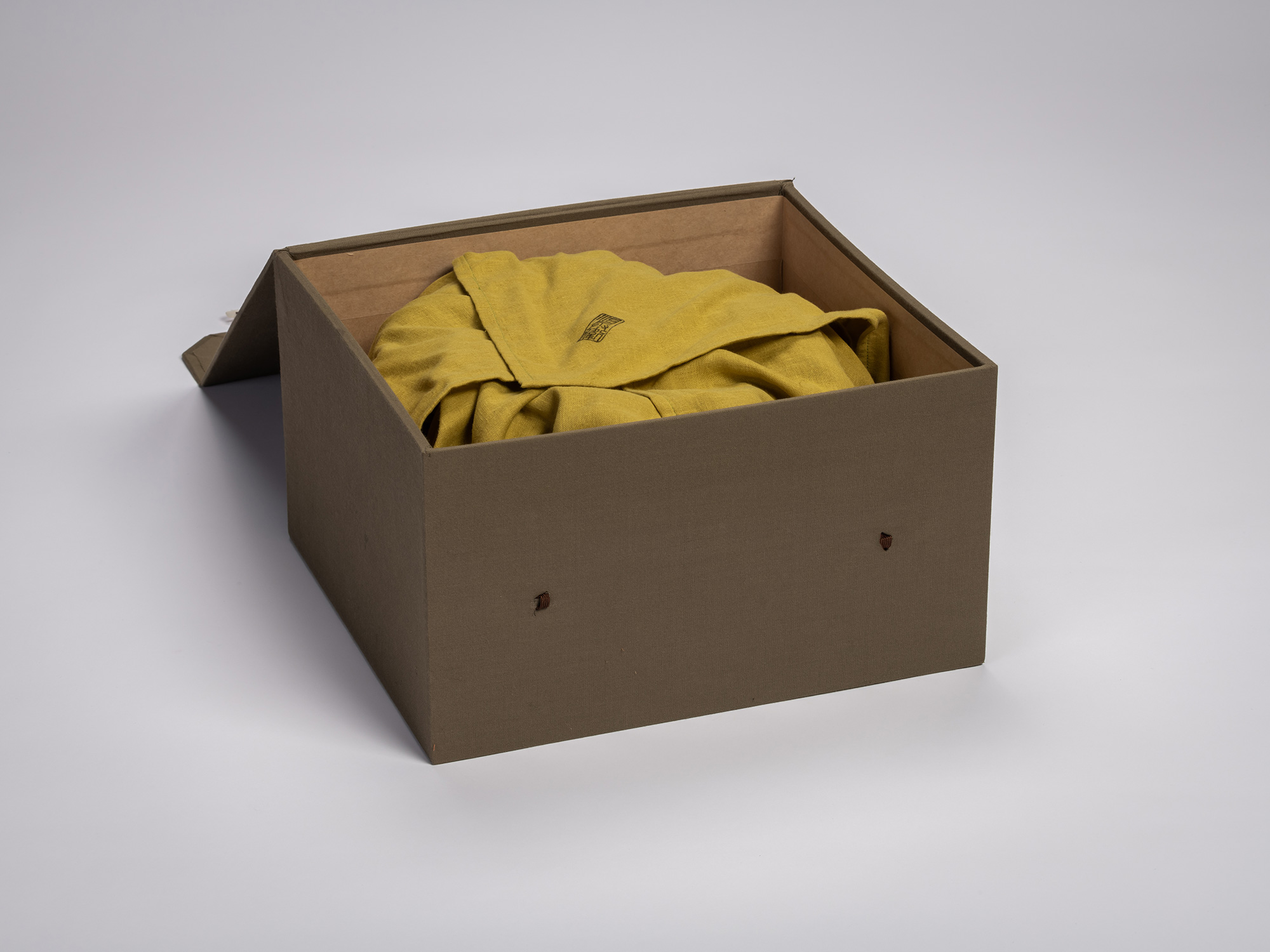 Open cloth-covered storage box containing artwork by Jihei Murase, showing the ceramic piece wrapped...