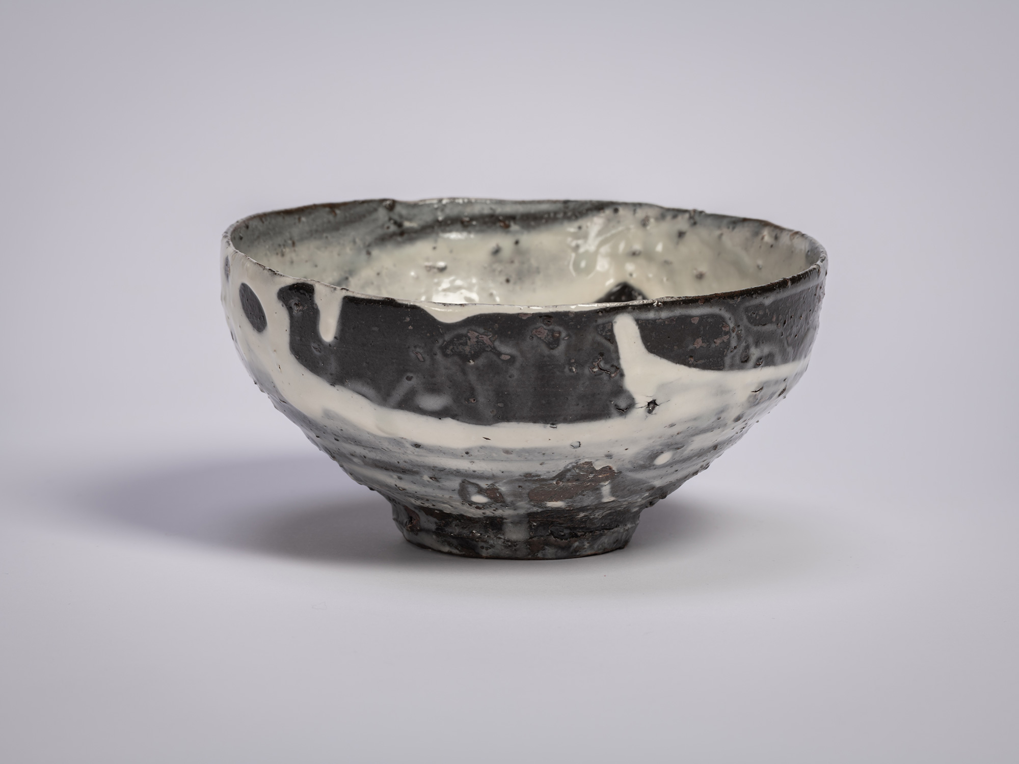 Hakeme tea bowl by Shiro Tsujimura, shown in profile, with a broad, gently flared form and a dark...