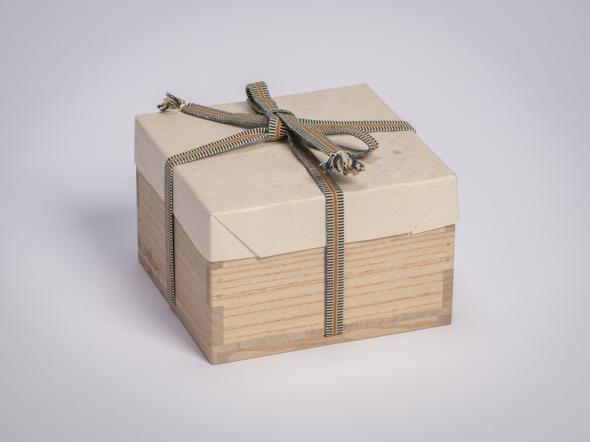 Square wooden tomobako (artist-signed storage box) by ceramic artist, shown with its mustard cloth...