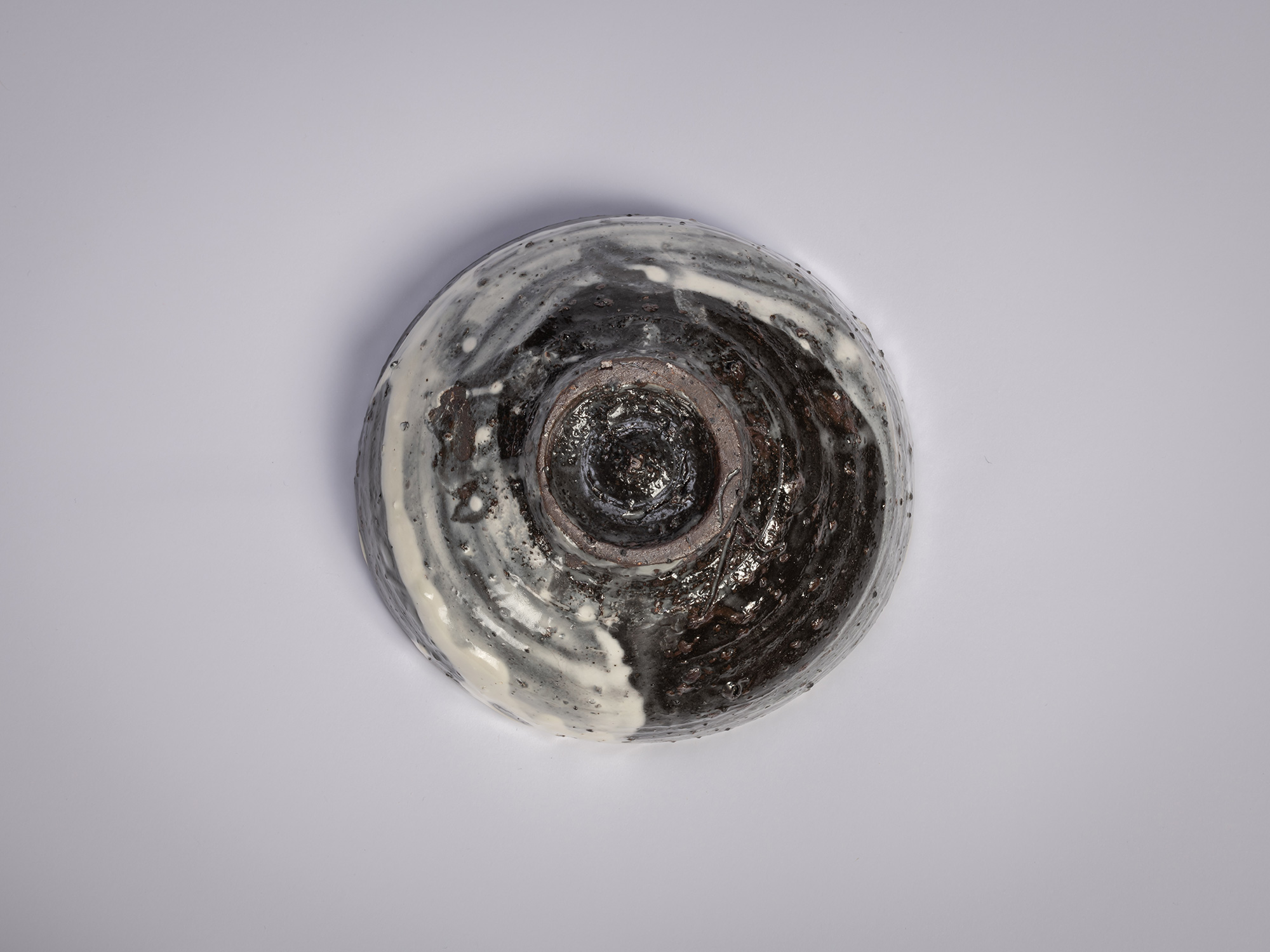 Underside view of the foot (kōdai) of a Hakeme tea bowl by Shiro Tsujimura, showing a roughly trimmed,...