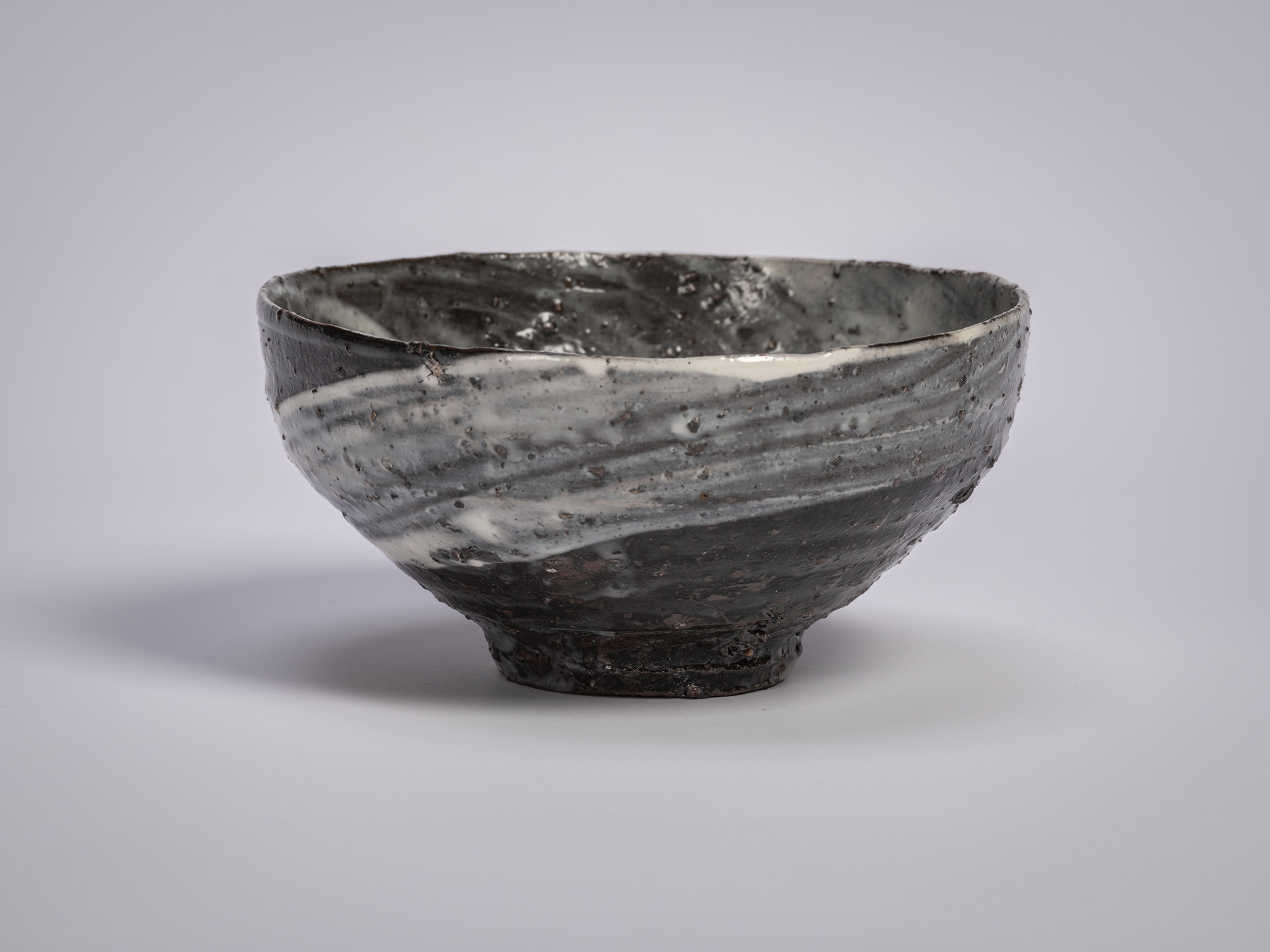Hakeme tea bowl by Shiro Tsujimura, shown in profile, with a broad, gently flared form and a dark...