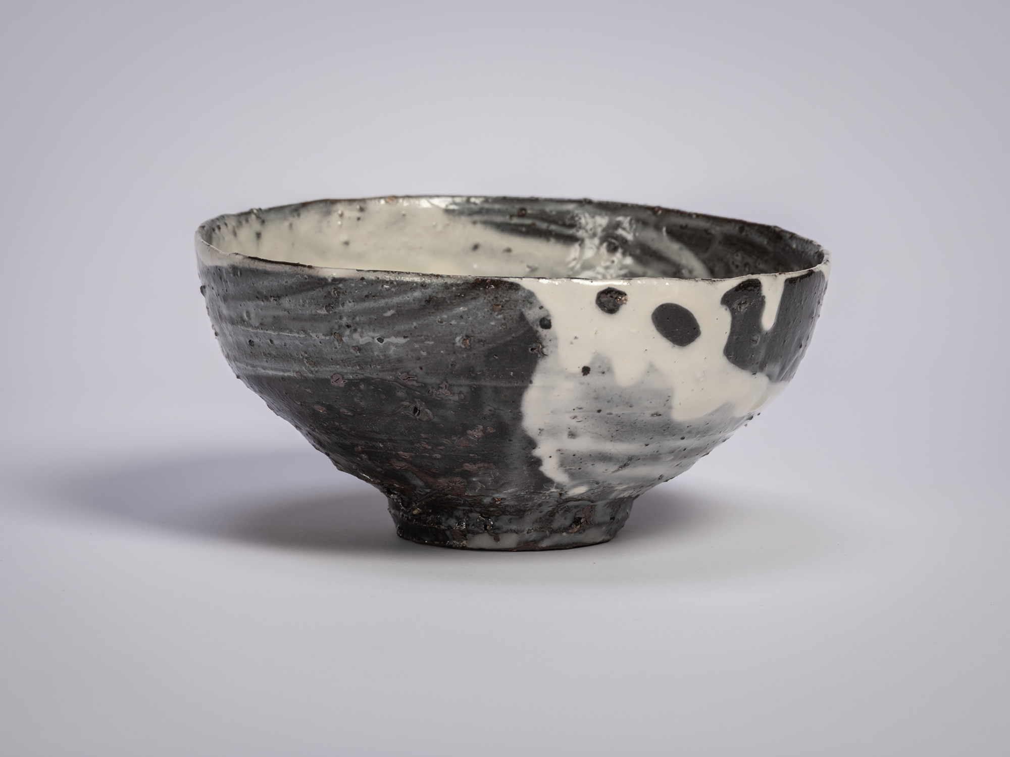 Hakeme tea bowl by Shiro Tsujimura, shown in profile, with a broad, gently flared form and a dark...