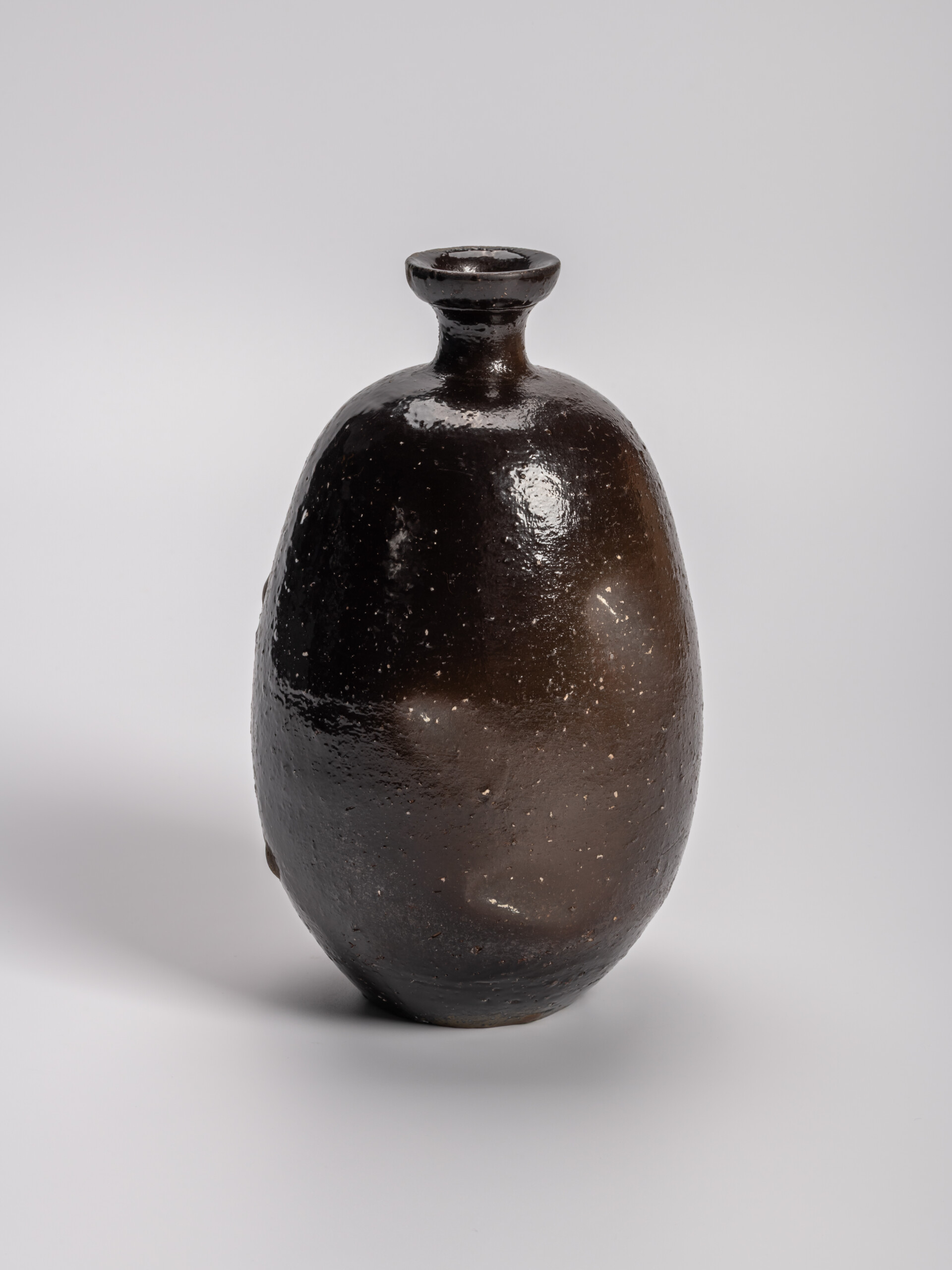 Dark, bulbous imo tokkuri (sweet potato–shaped sake flask) by Ryuichi Kakurezaki, with a rounded...