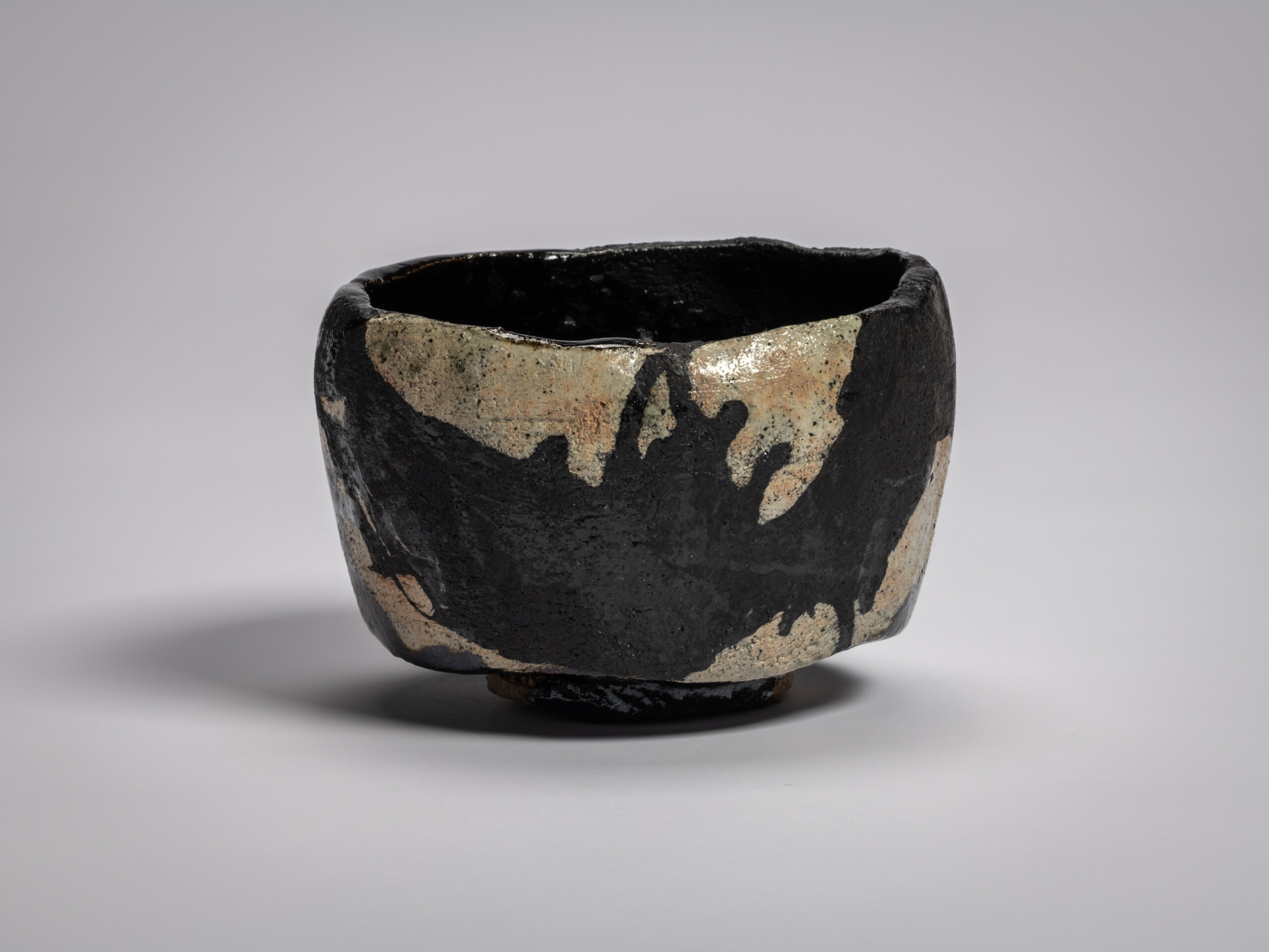 Black Raku tea bowl titled Old Plum Tree, primary view with irregular hand-formed rim, matte black...