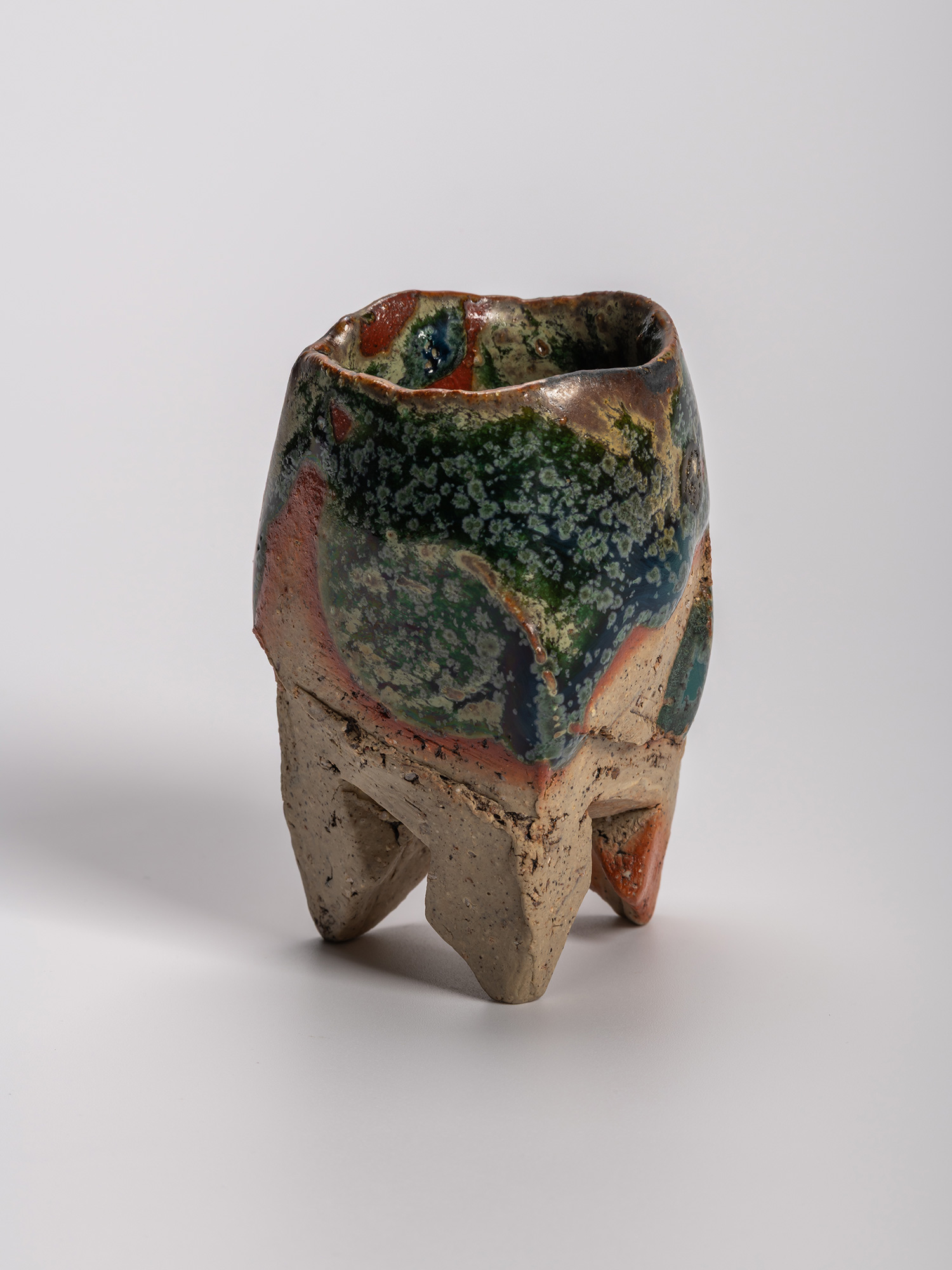 Iron Oribe sake cup with irregular faceted form, copper-green glaze, and iron-rich clay body, showing...