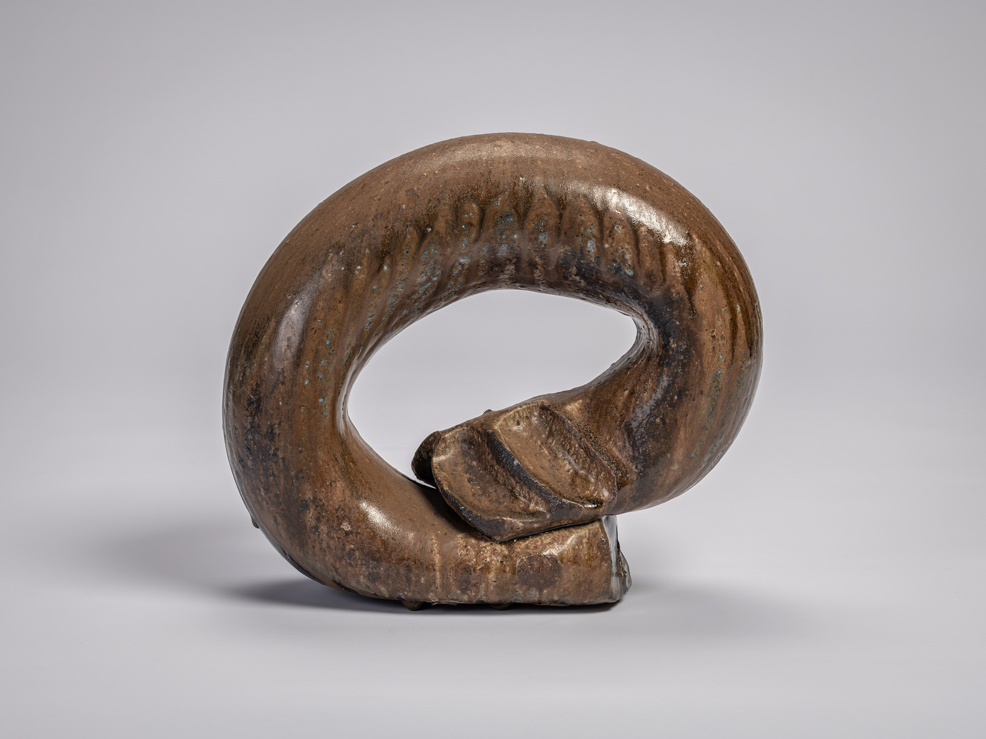 Front view of the ceramic sculpture Ring by Jun Isezaki, featuring a dark thick circular form with...