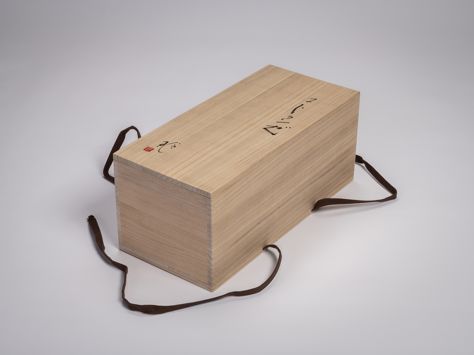 Wooden tomobako (storage box) for the iron sculpture Sai by Aki Rusu, shown closed with brown fabric...