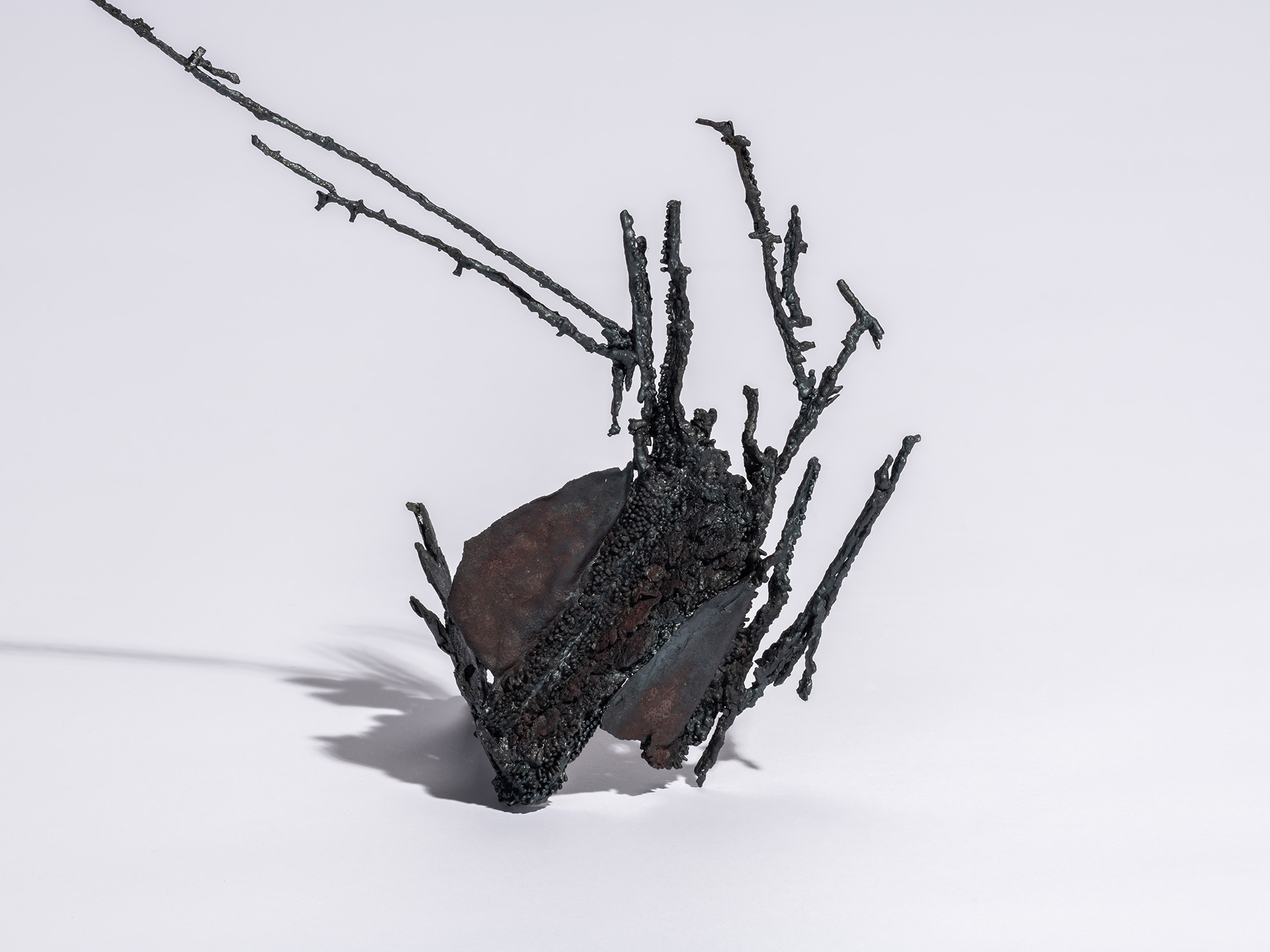 Detail of welding of Iron sculpture Sai by Aki Rusu, featuring a clustered, organic base of dark...