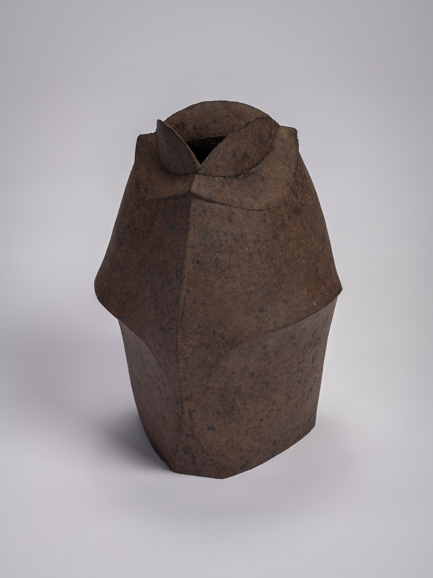 Front view of a black stoneware triangular jar by Mori Tōgaku, featuring sharply faceted sides,...