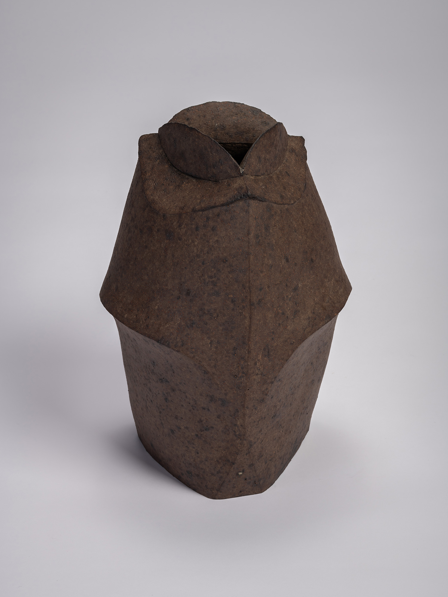 Front view of a black stoneware triangular jar by Mori Tōgaku, featuring sharply faceted sides,...