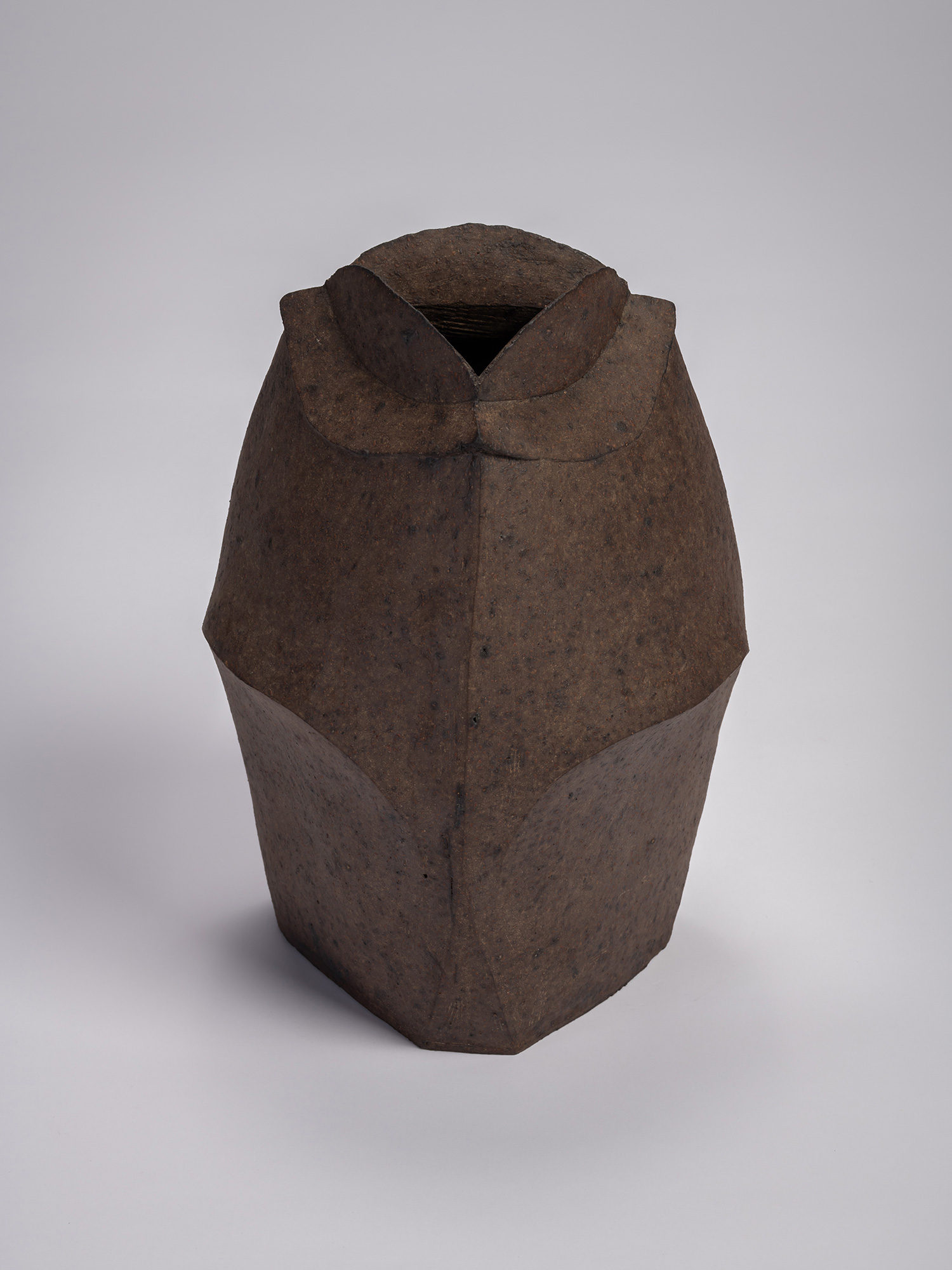 Front view of a black stoneware triangular jar by Mori Tōgaku, featuring sharply faceted sides,...