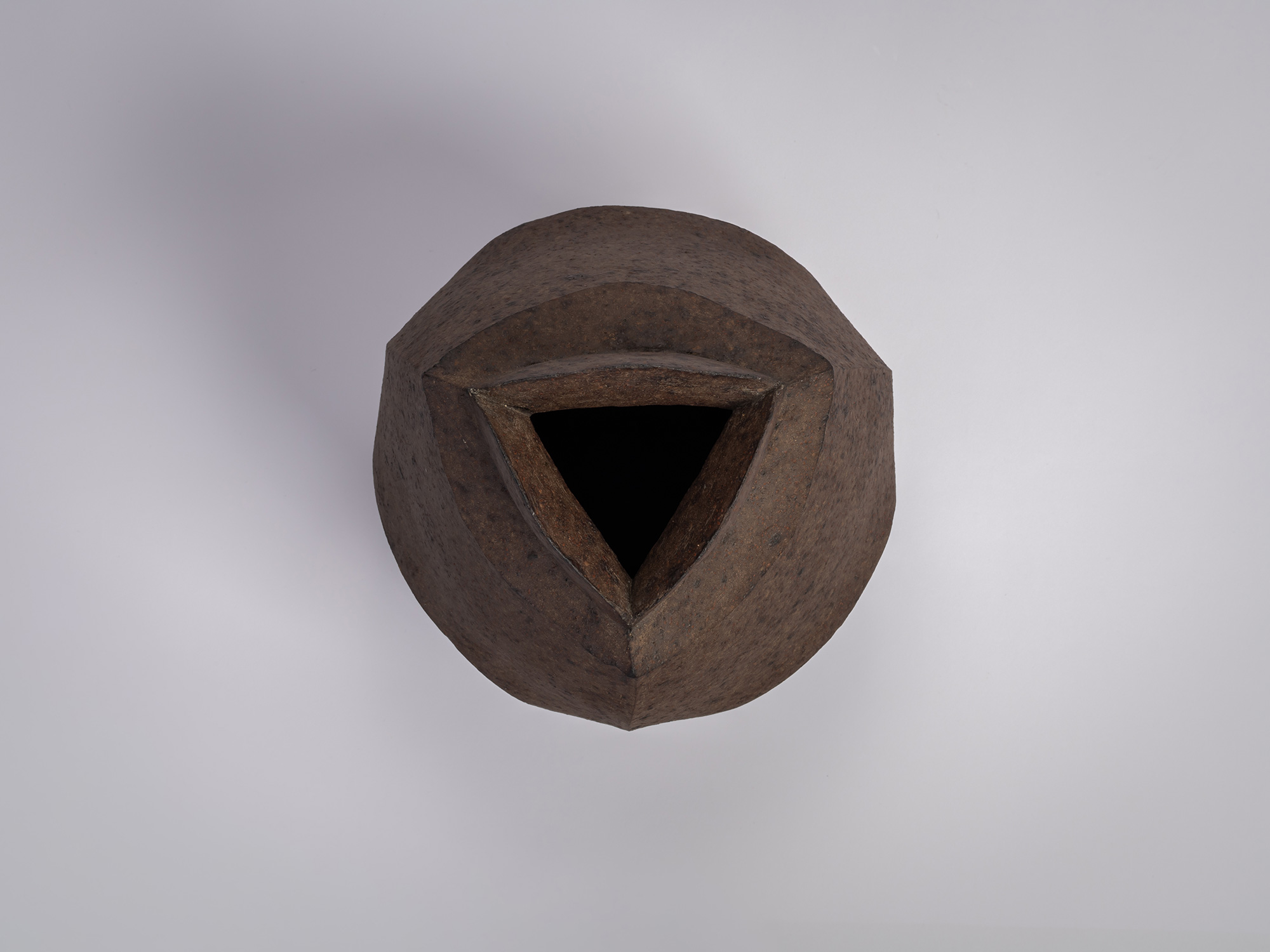 Top-down view of a black stoneware triangular jar by Mori Tōgaku, showing the sharply defined triangular...
