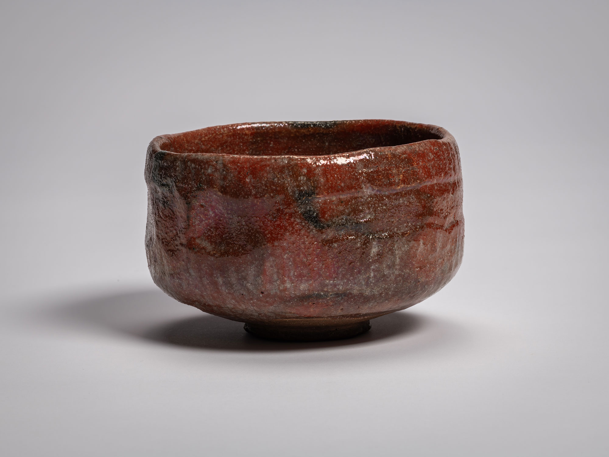 Profile view of the authentic red Raku tea bowl named Asahi (Morning Sun), handcrafted by Raku...