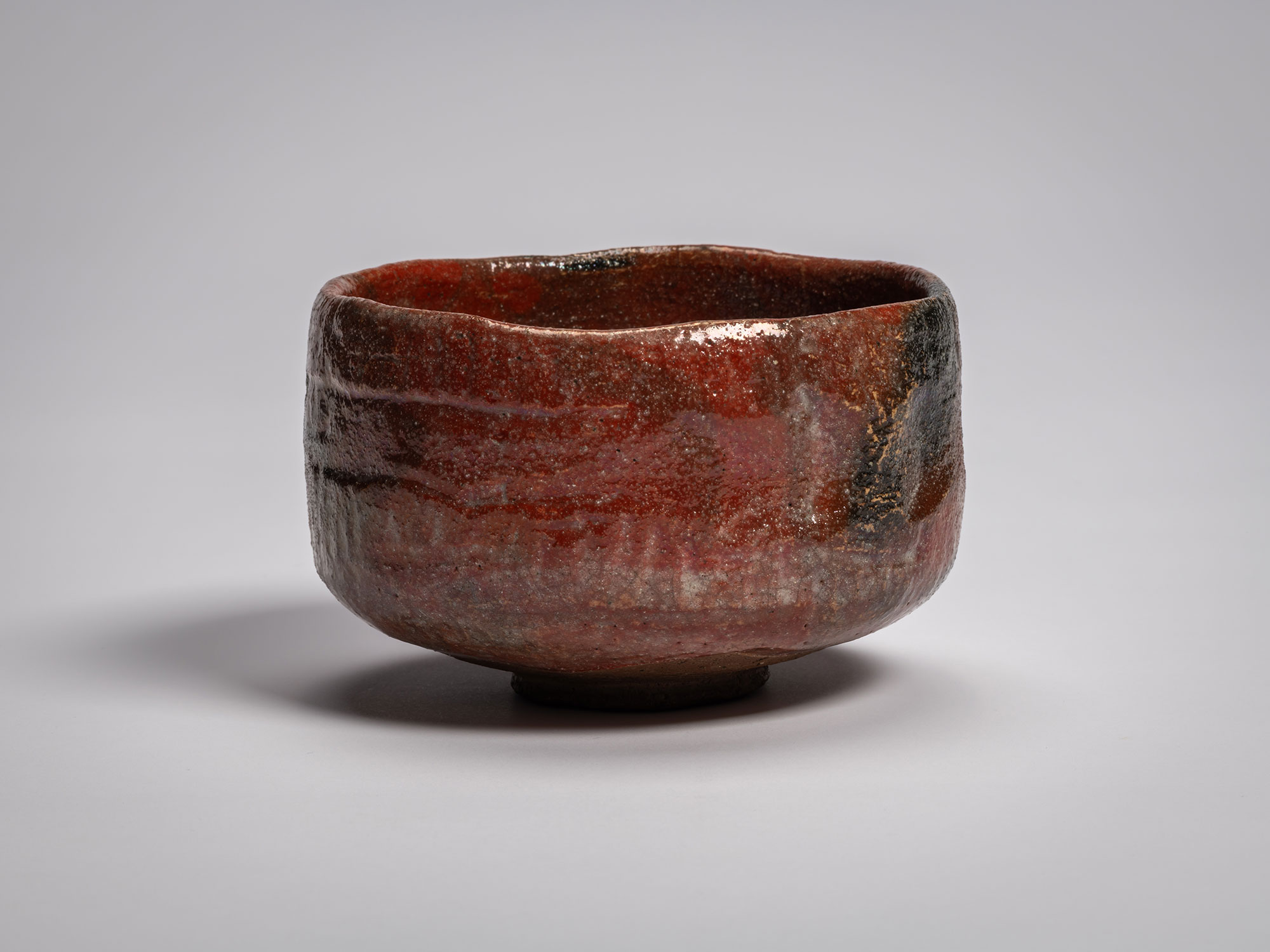 Profile view of the authentic red Raku tea bowl named Asahi (Morning Sun), handcrafted by Raku...