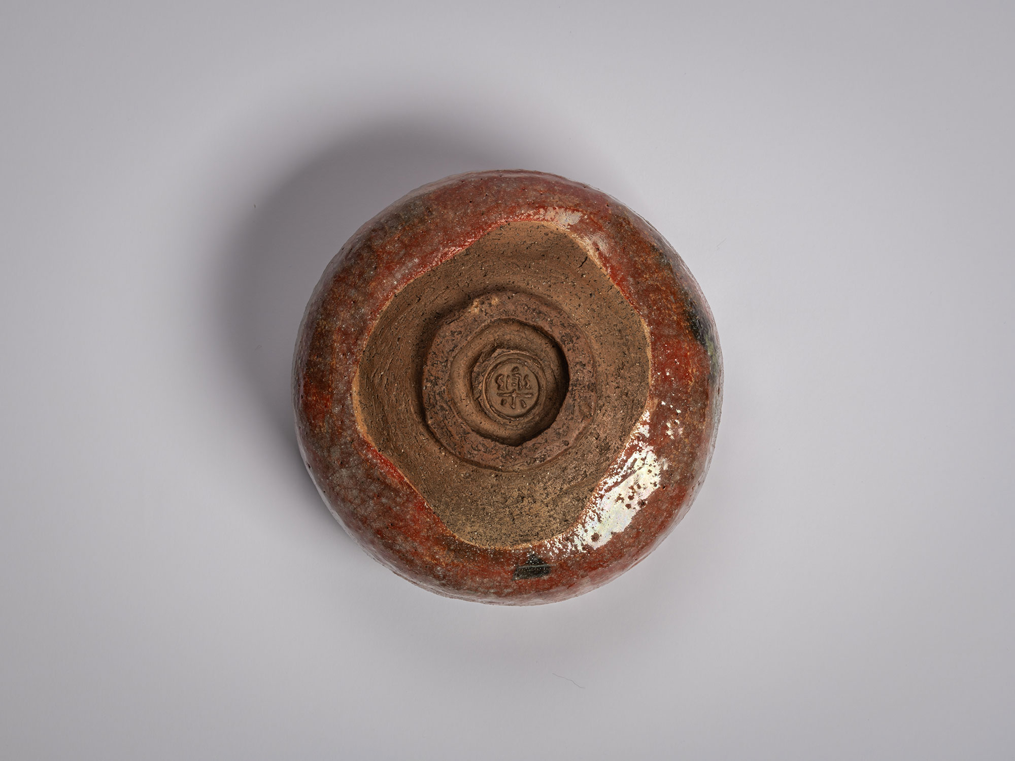 Overhead view of the base (kodai) of the Asahi red Raku tea bowl, showcasing the unglazed earthen...