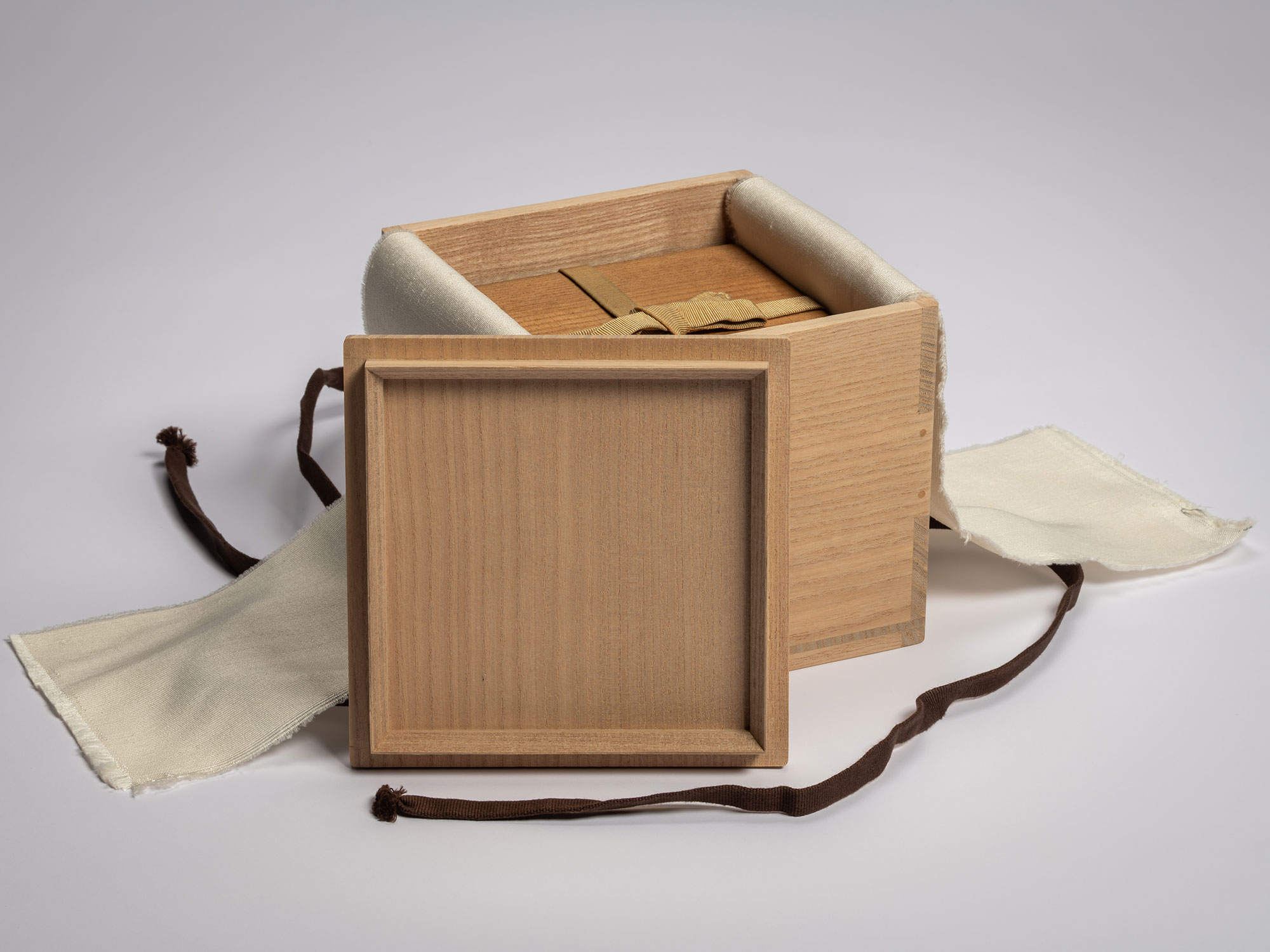 Gemini said Exterior view of a light-toned paulownia wood box (tomobako) shown open to reveal a...